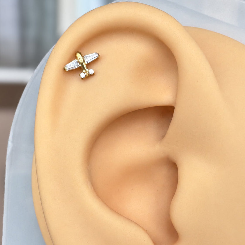 Airplane flat back stud with CZ wings displayed on silicone ear.