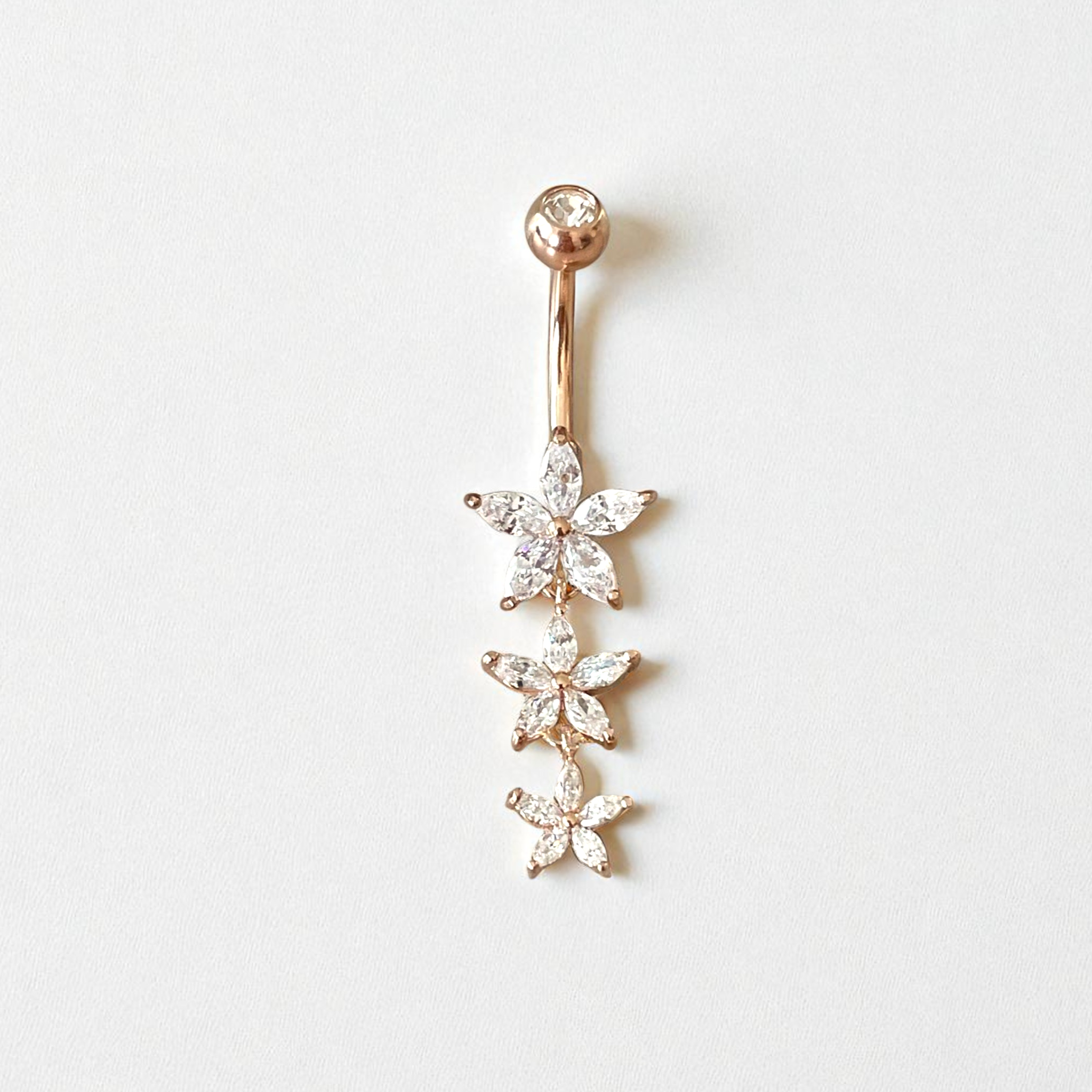 Rose gold belly button ring with three clear crystal flower charms