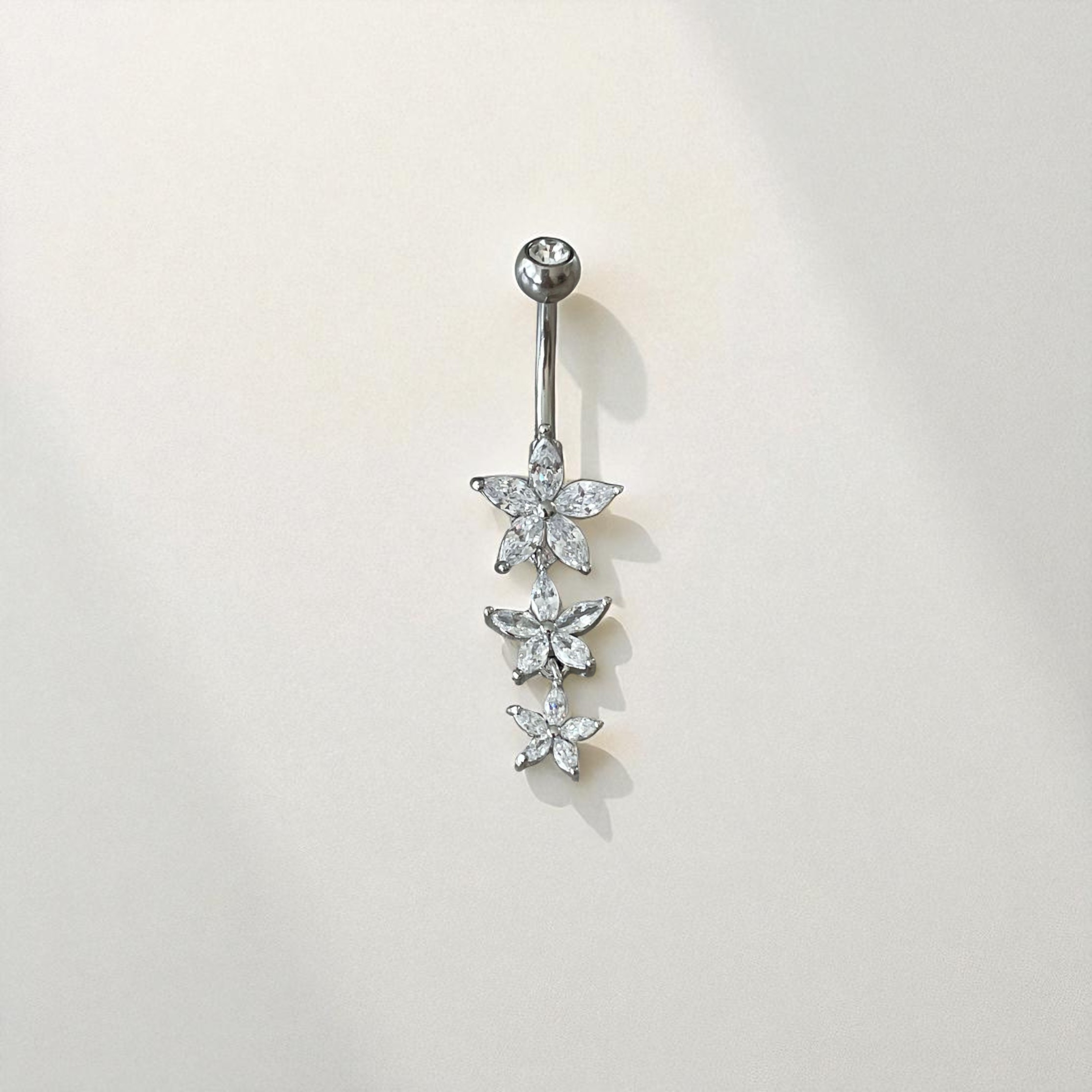 Silver belly button ring with floral design on a light gray background