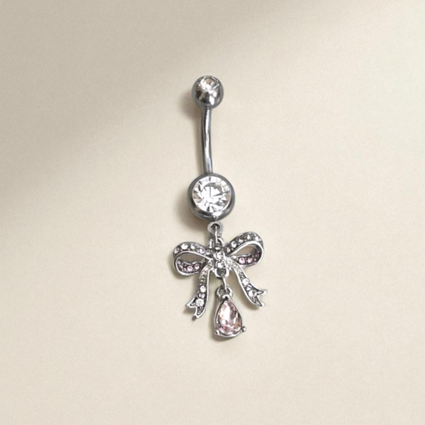 Silver Belly button ring with bow and gemstone design on a beige background