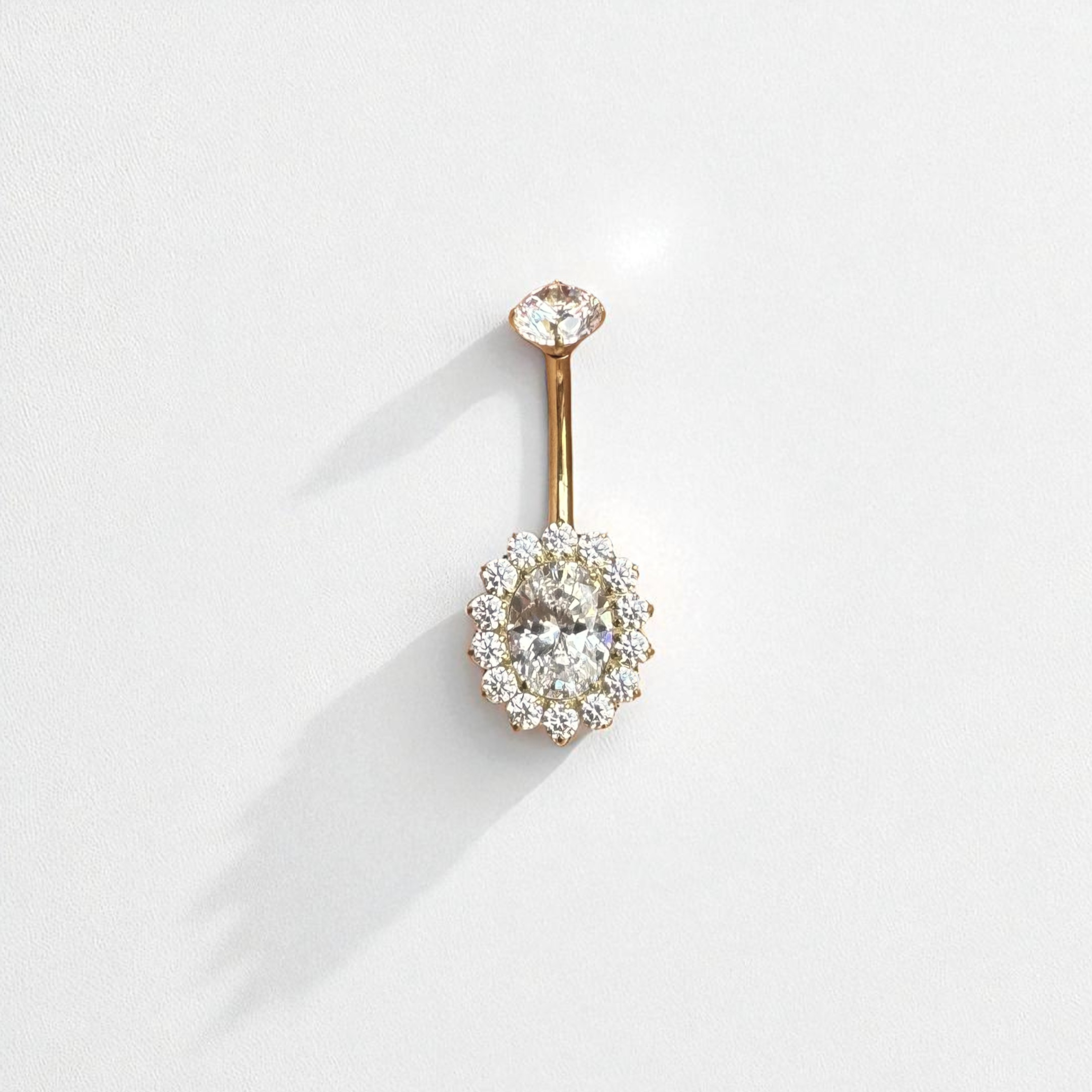 Gold belly button ring with clear gemstones on a white background
