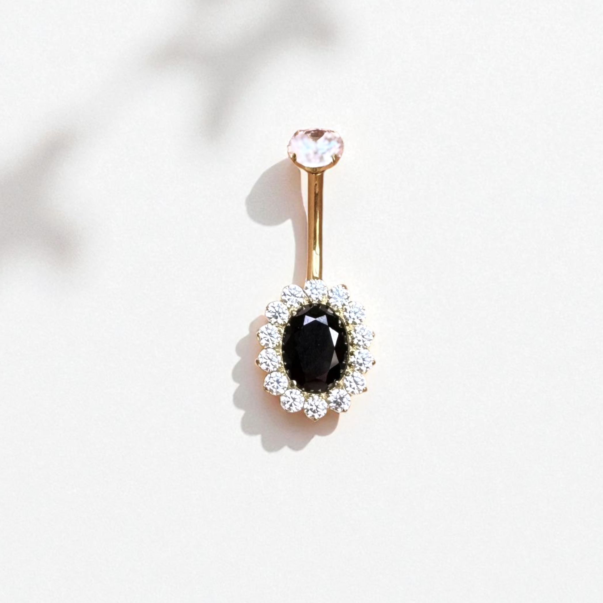 Gold belly button ring with black gem surrounded by a halo of clear gems
