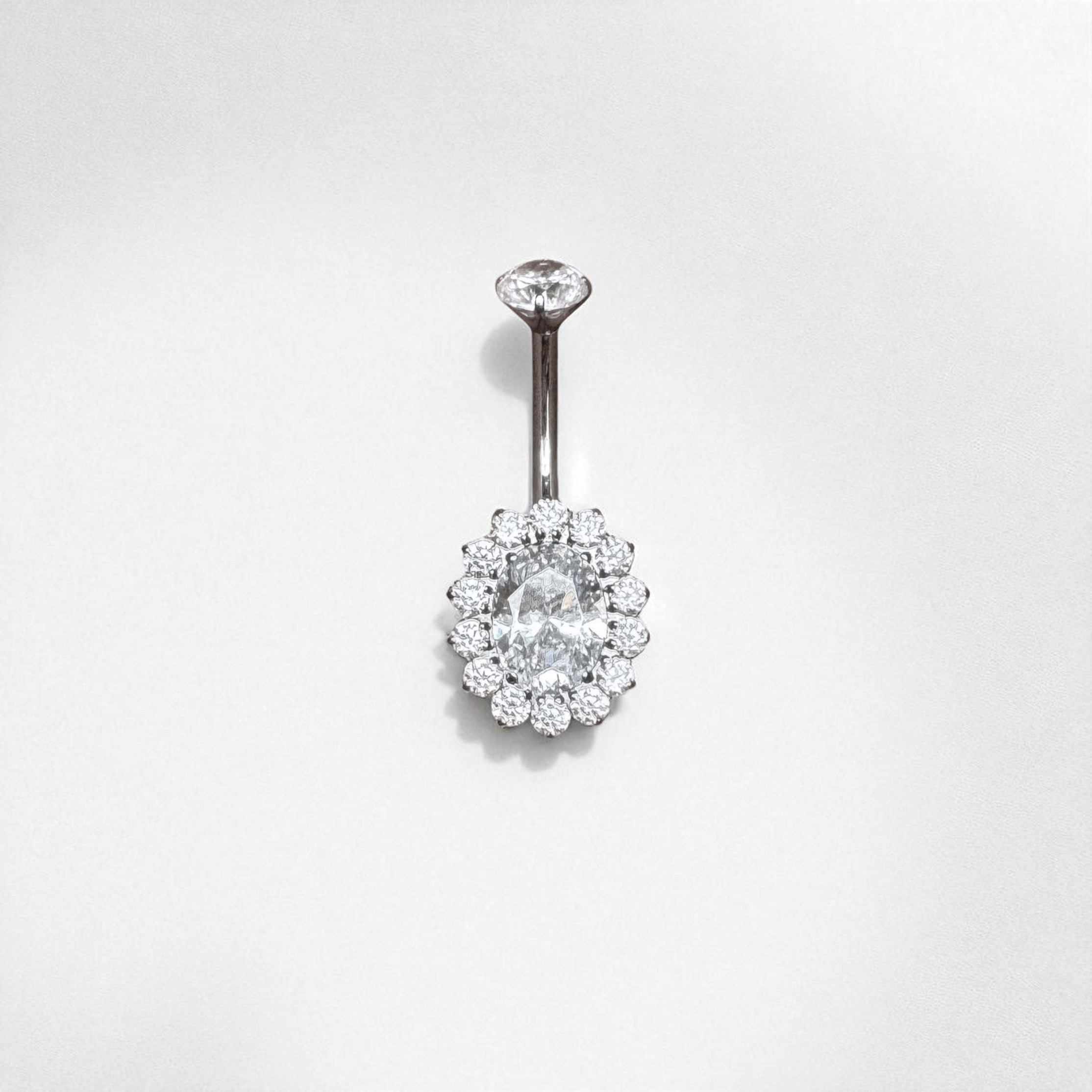 Belly button ring with clear gemstones on a light gray background