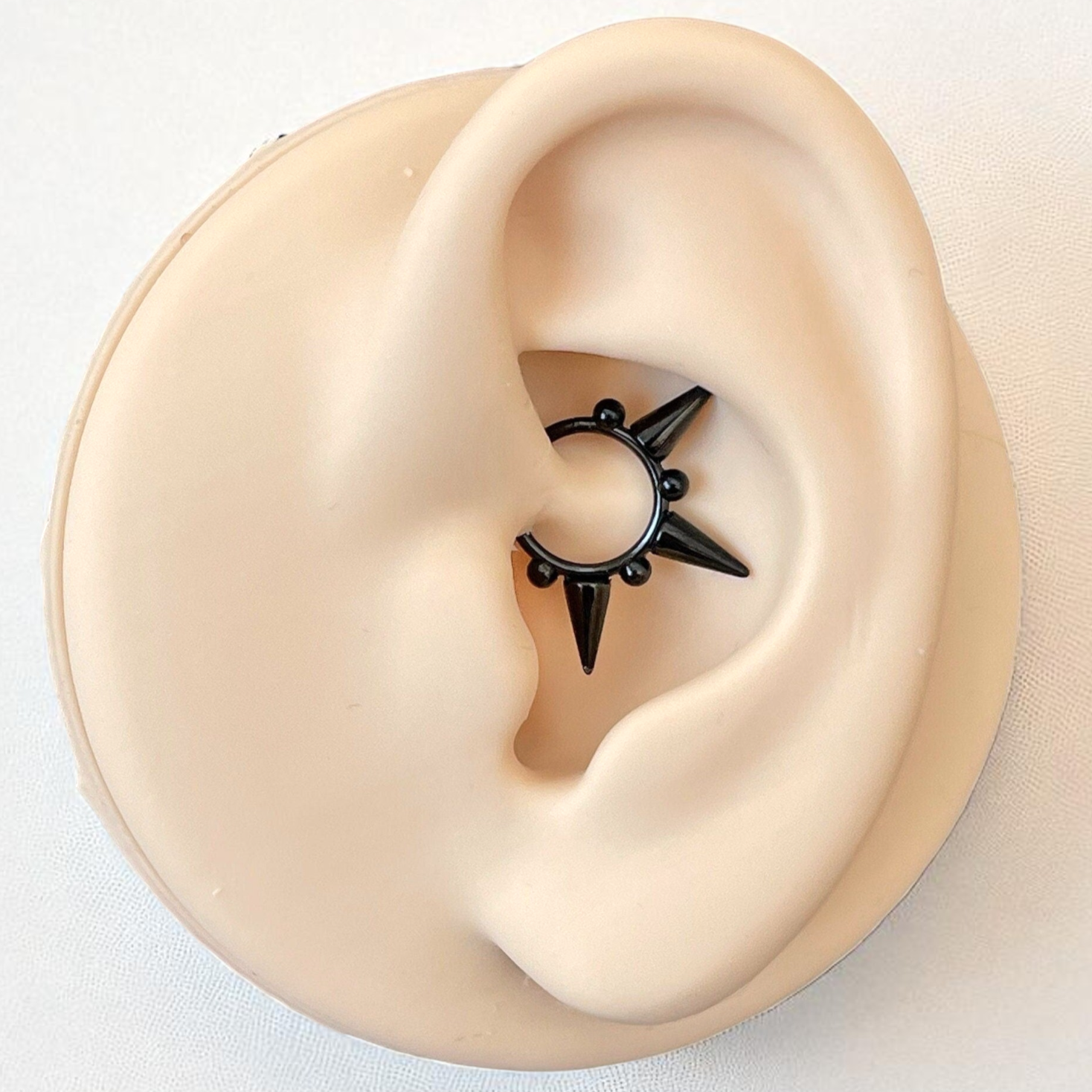 Black daith earring
on a model ear with a plain background