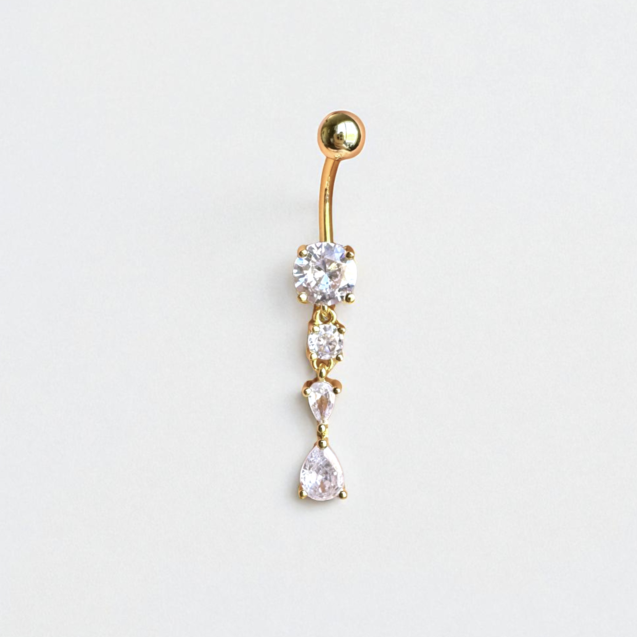 Gold belly button ring with clear gemstones on a light gray background