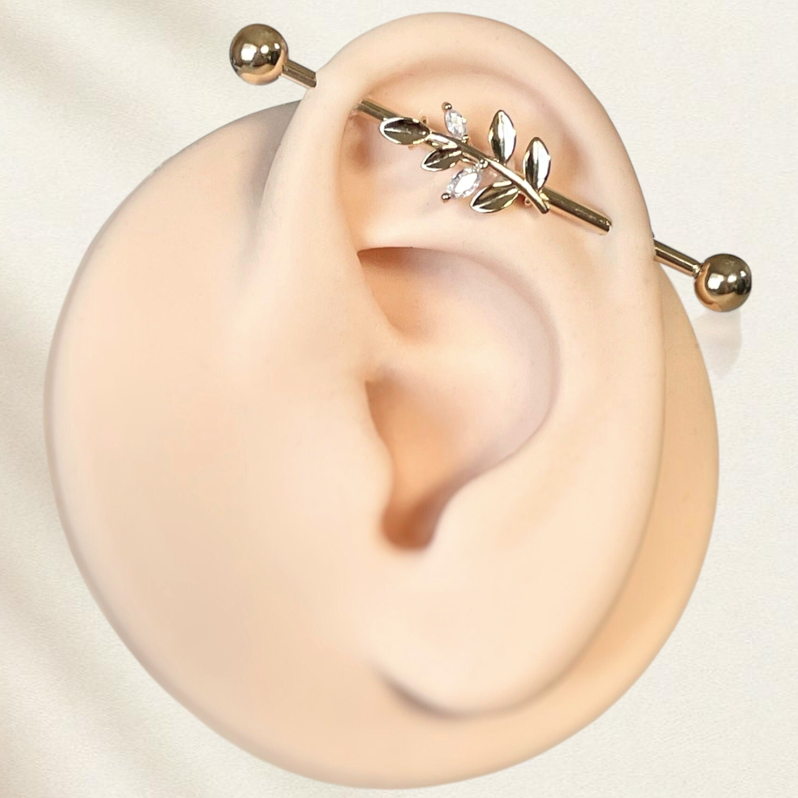 Gold industrial earring with leaf motif on silicone ear