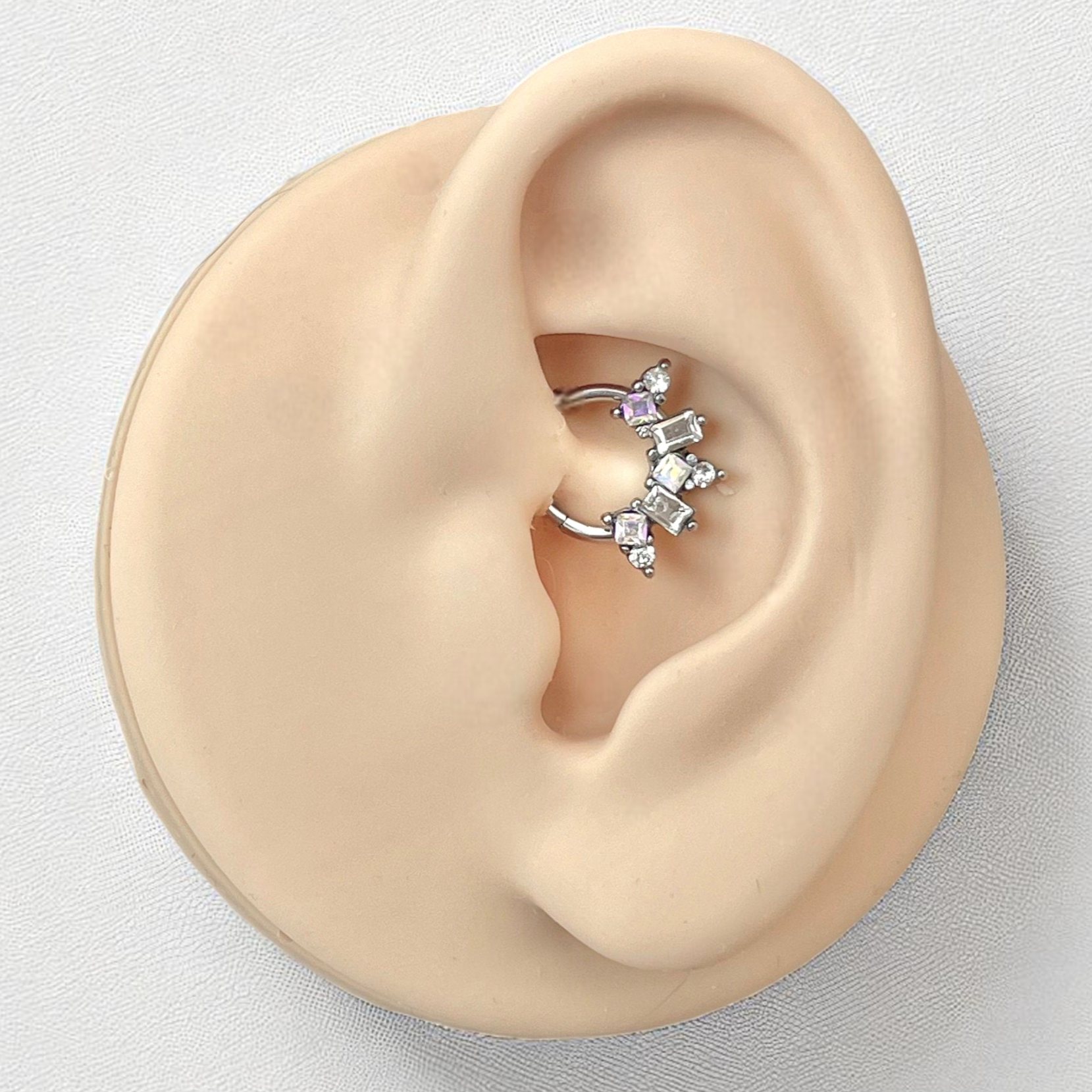 Close-up of an ear wearing a geometric daith earring on a light gray background