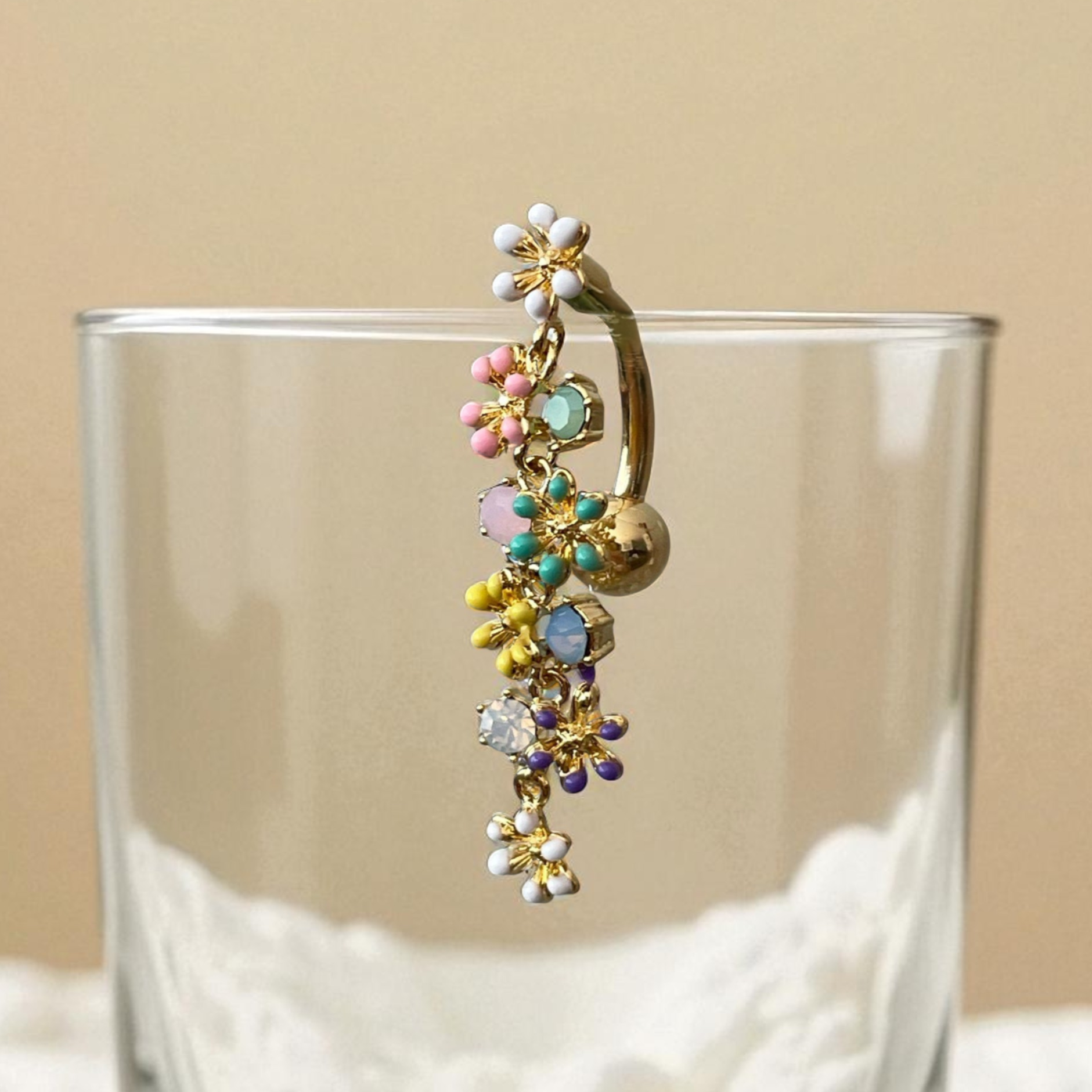 Colorful floral belly button ring
on a clear glass with a beige background