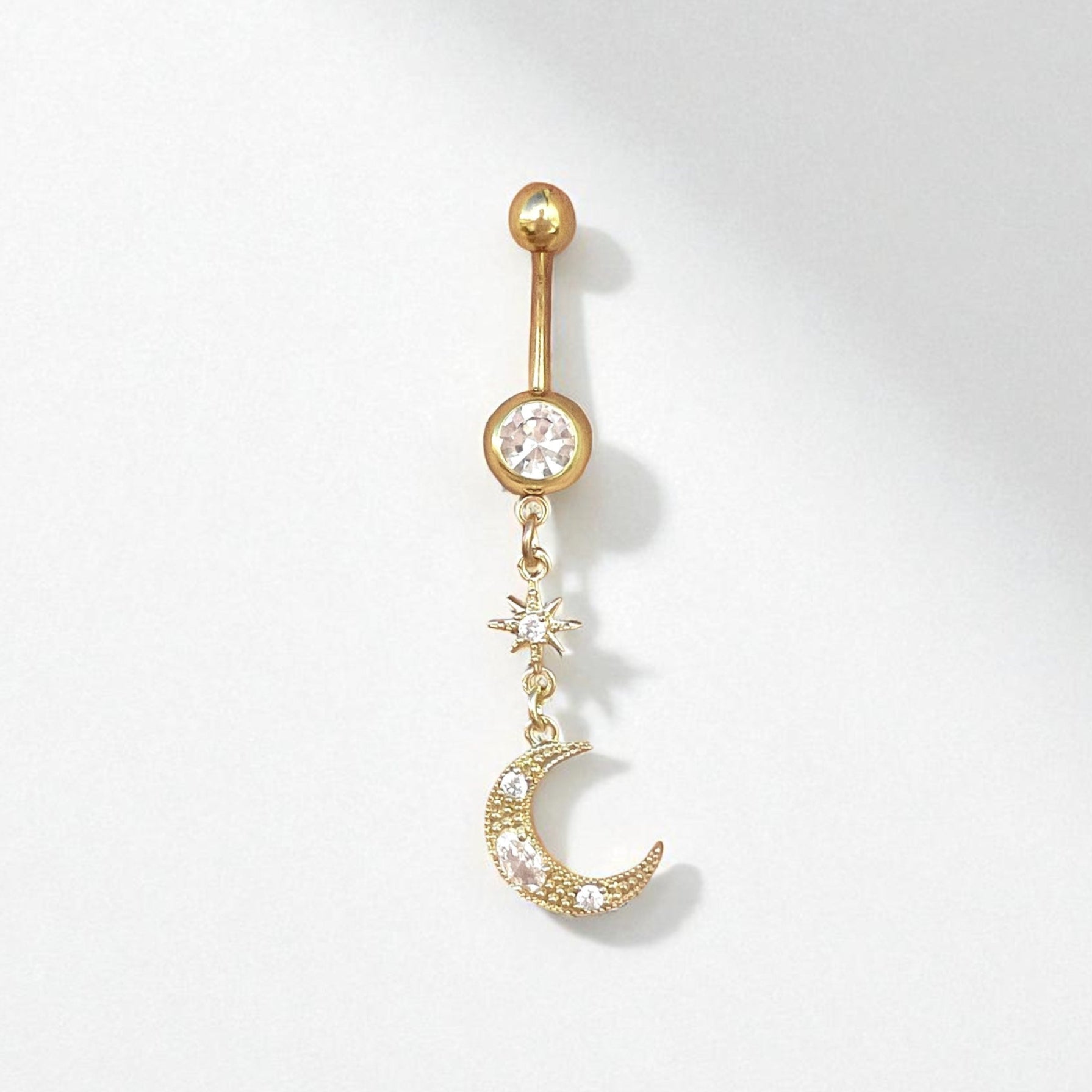 Gold belly button ring with a moon and star design on a white background