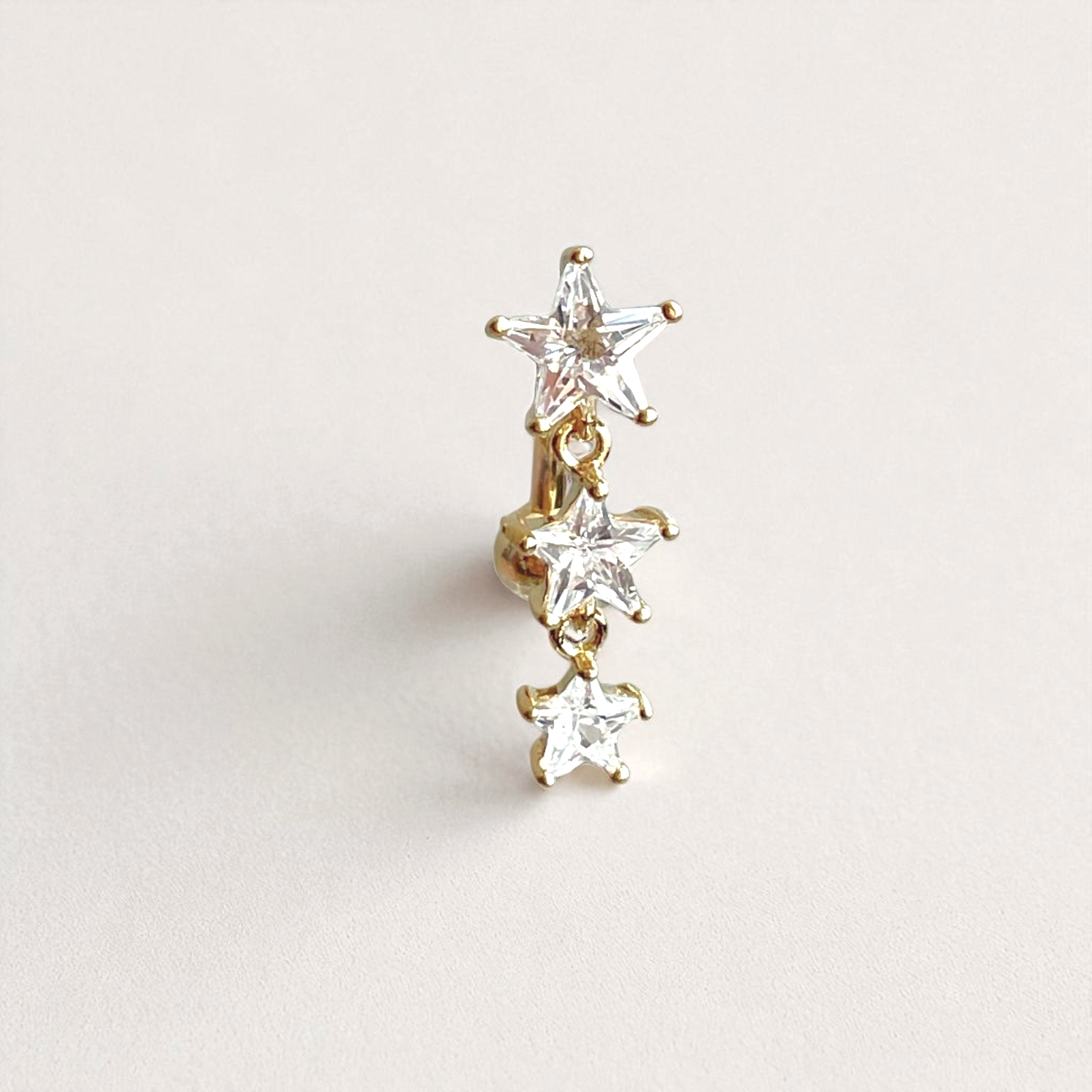 Star-shaped belly button ring with clear stones on a light gray background