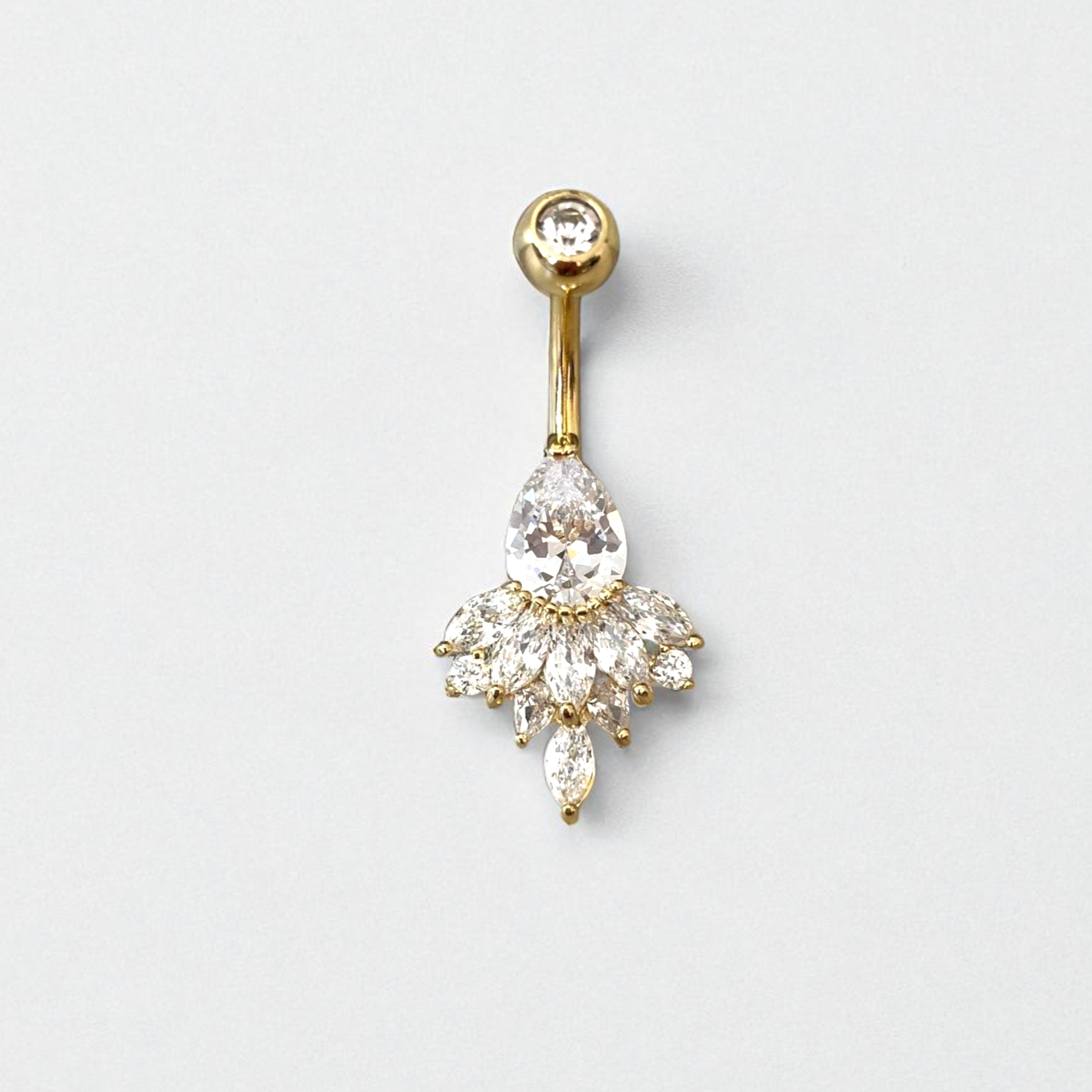 Gold belly button ring with clear gemstones on a light gray background