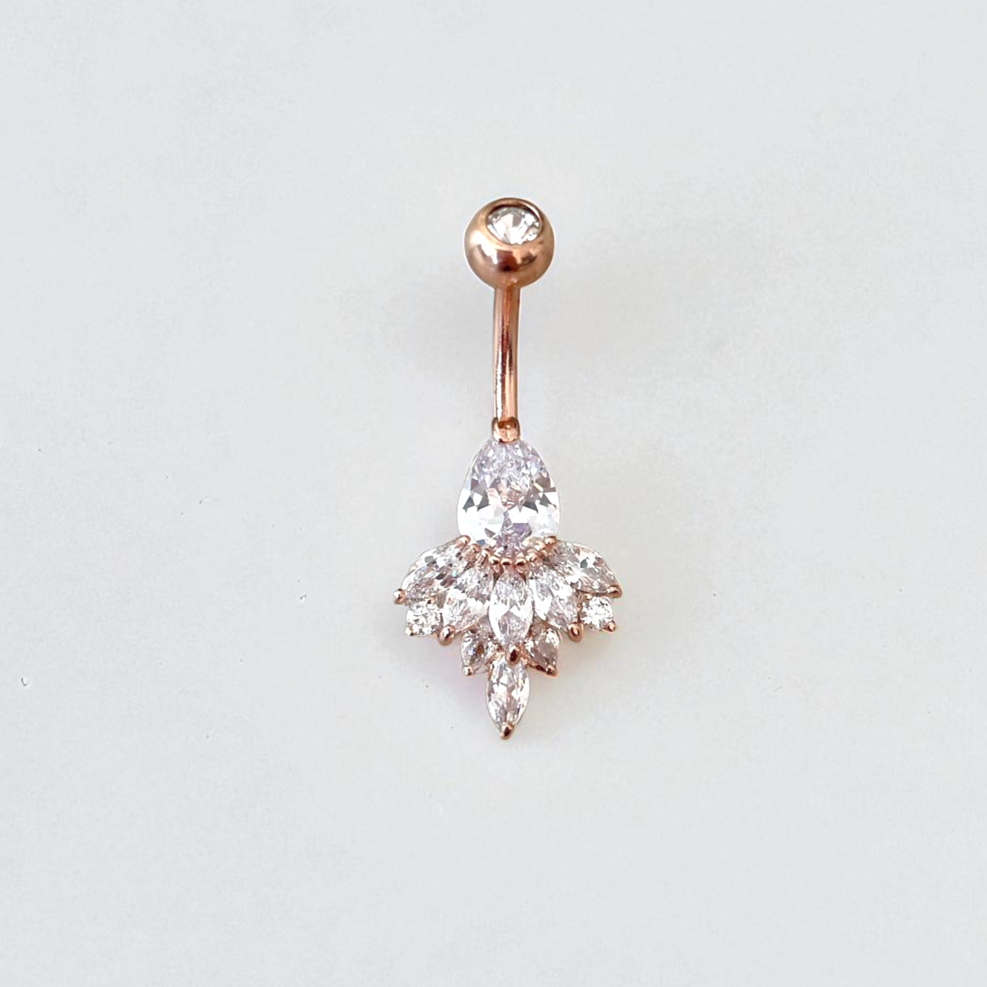 Rose gold belly button ring with clear gemstone on a light gray background