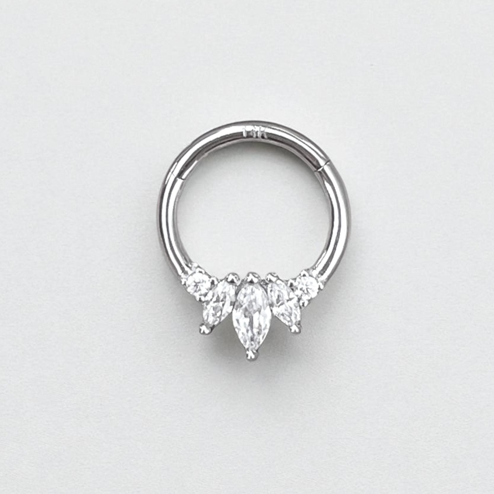 Silver nose ring with three teardrop-shaped gemstones on a light gray background