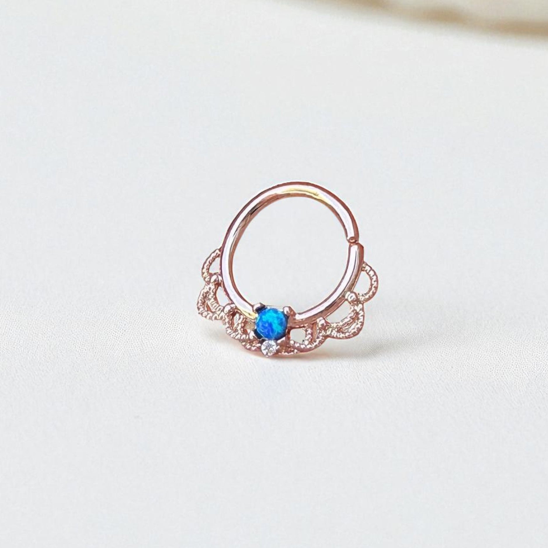 Rose gold ring with a blue opal on a light background