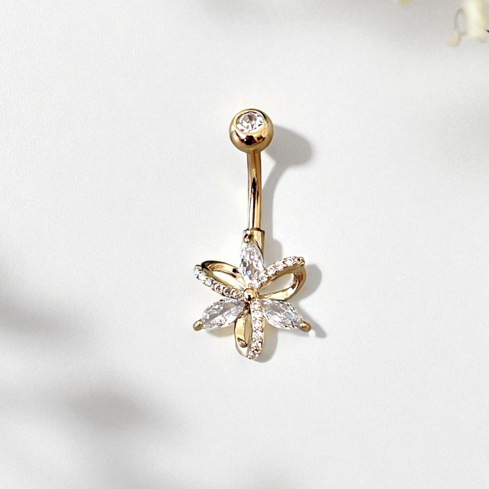 Flower belly button ring in gold, on a white background
