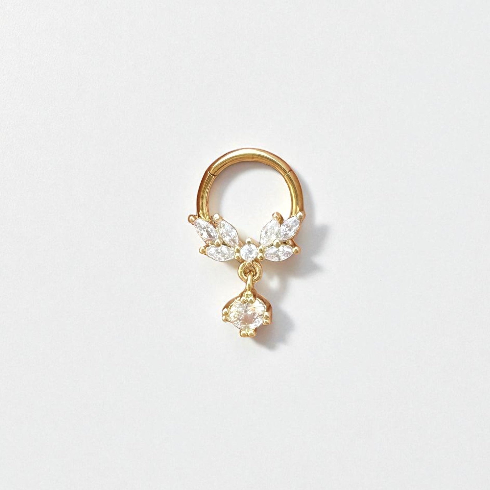 Gold daith earring with crystal and butterfly charm on a light gray background