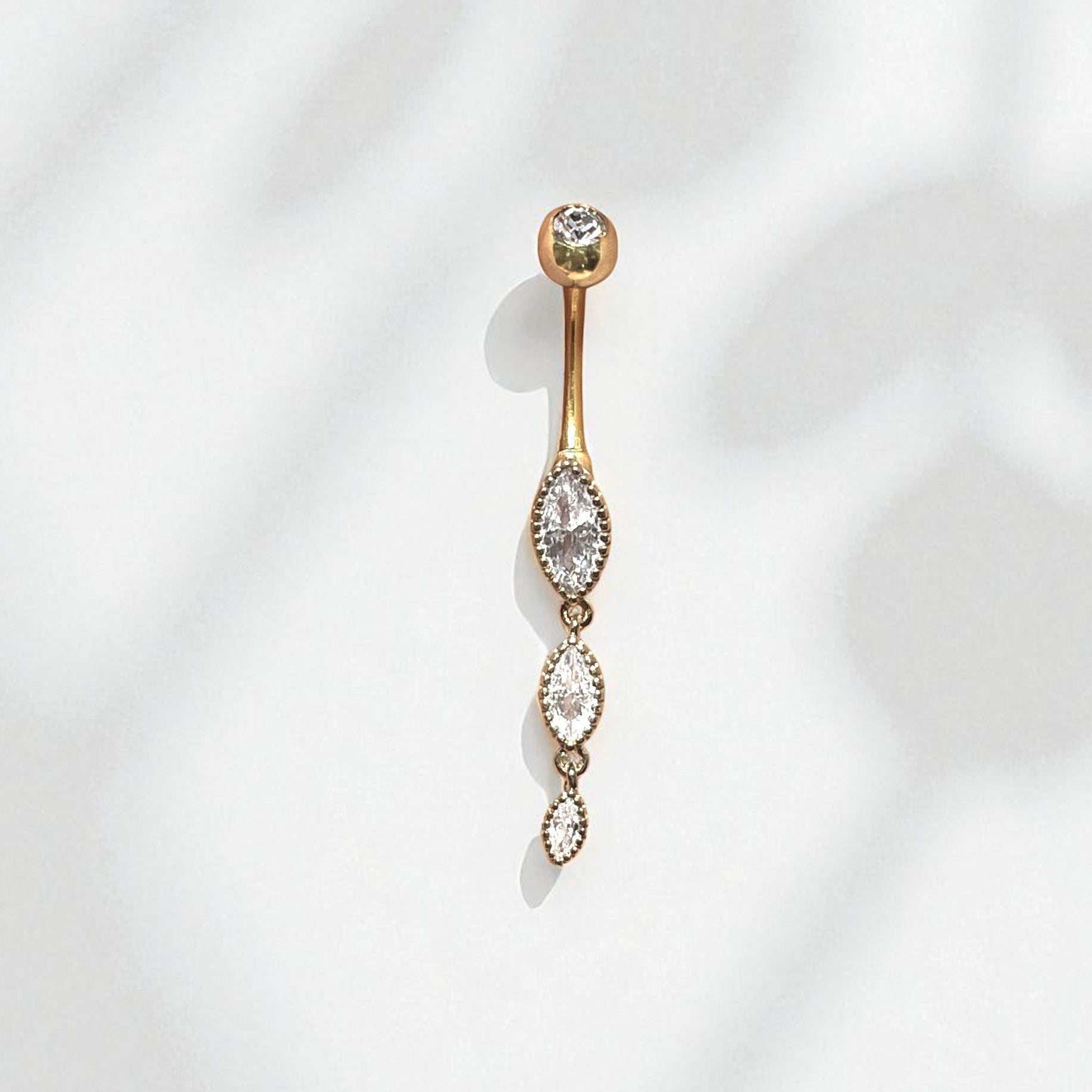 Gold belly button ring with clear marquise gemstones on a white background