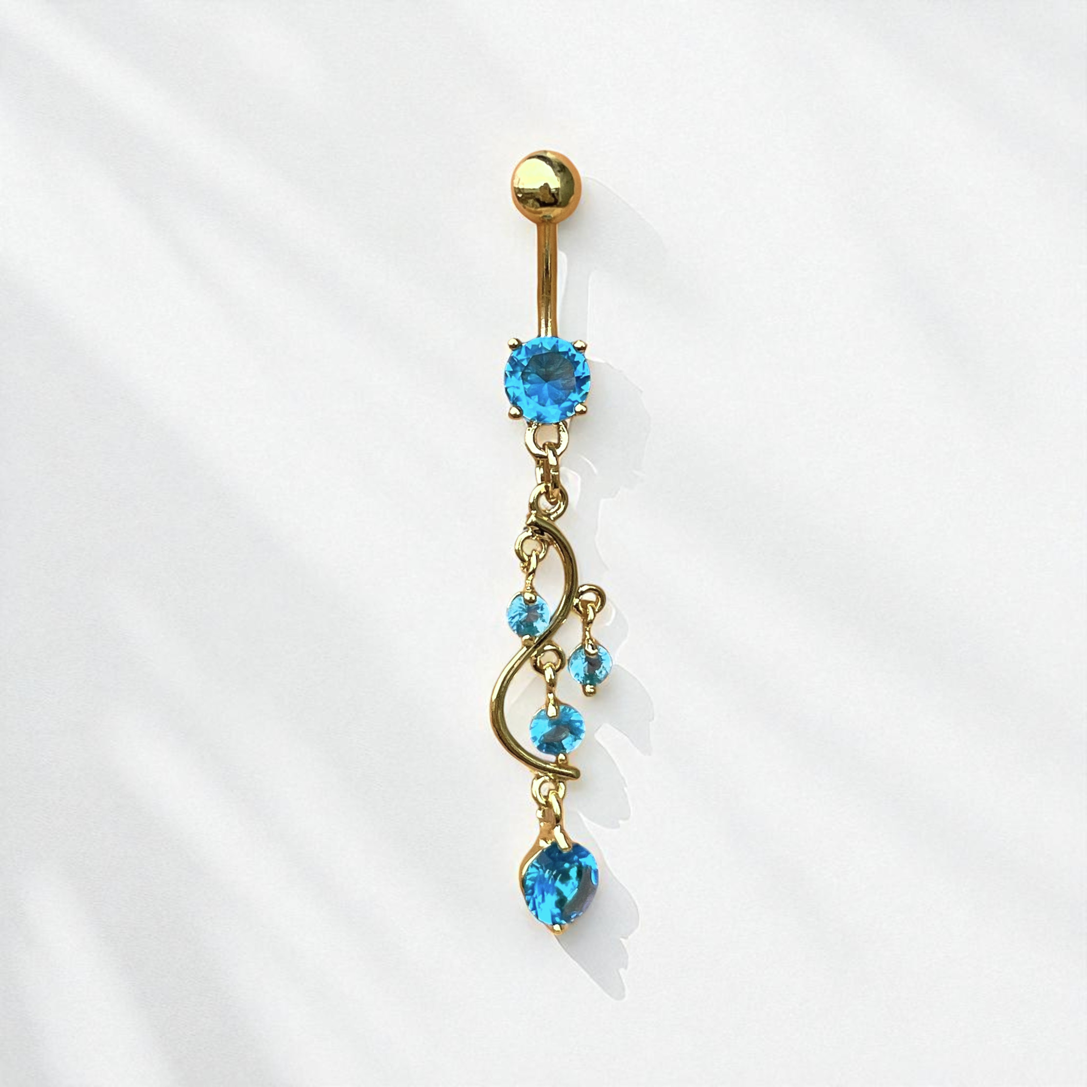 Gold belly button ring with blue gemstones on a white background