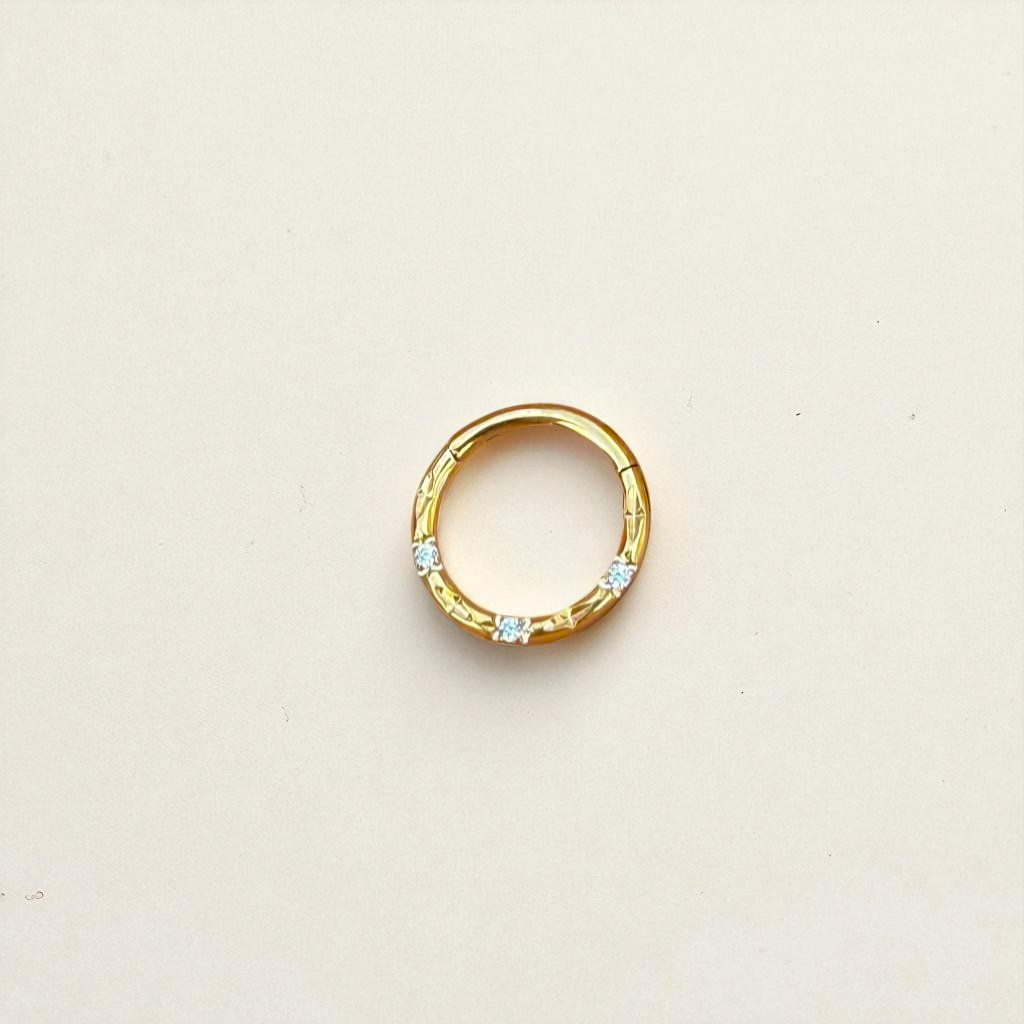 Gold ring with embedded stones on a beige background