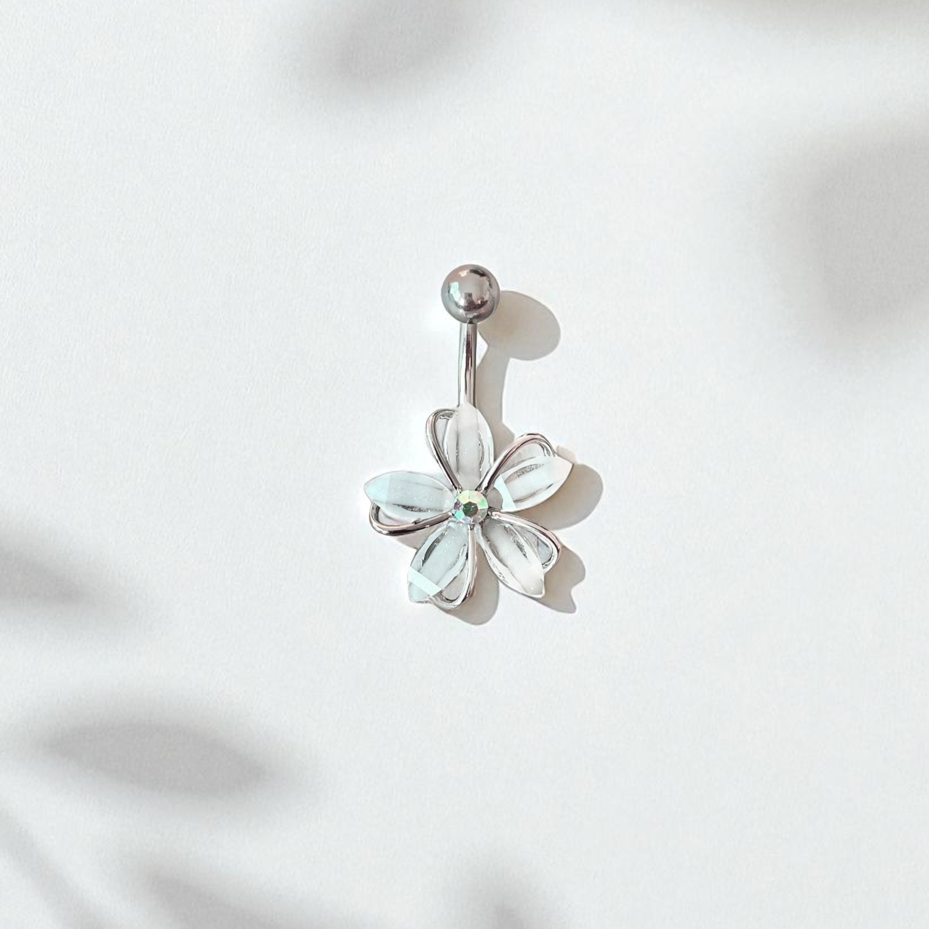 Flower-shaped belly button ring on a light pink background