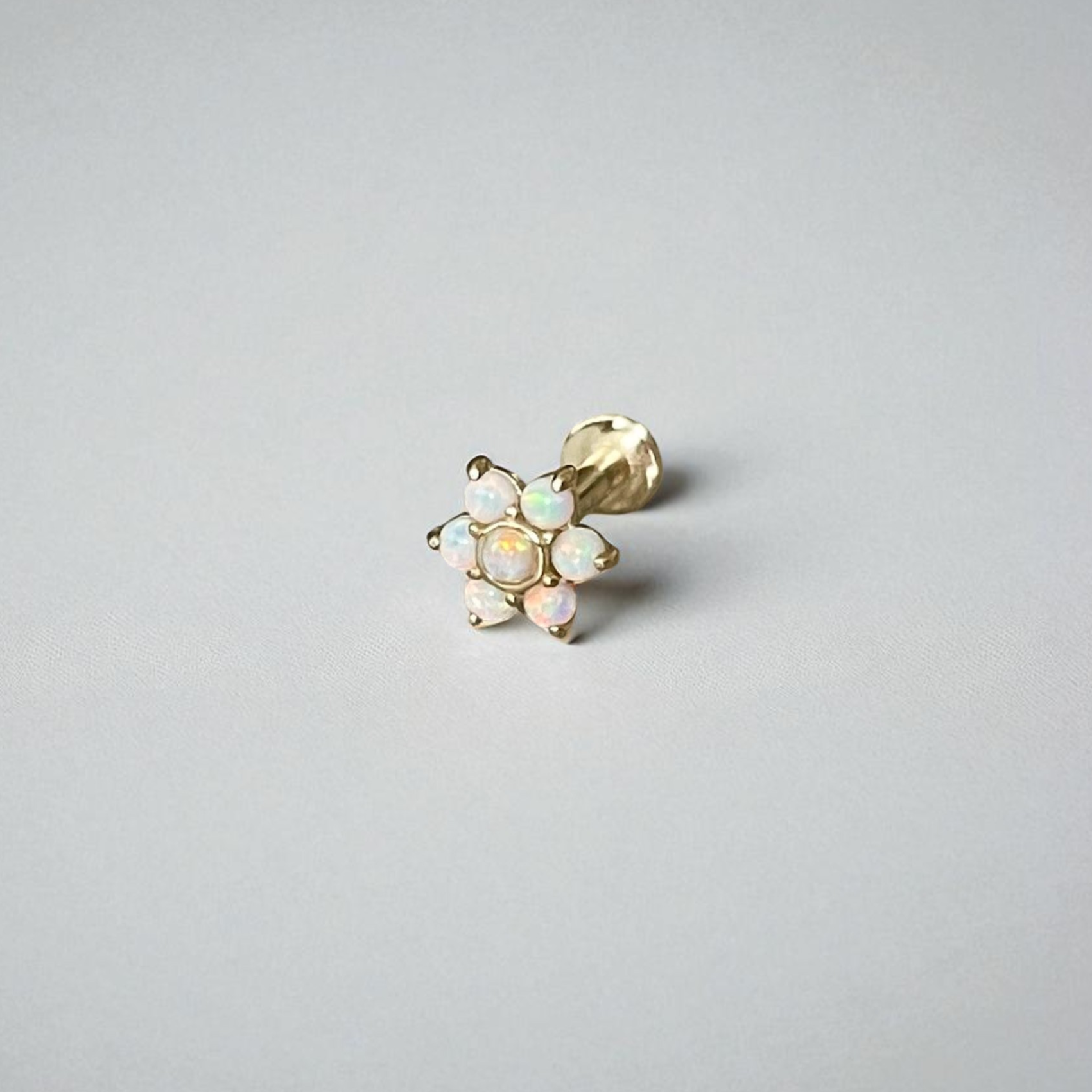 Gold earring with opal stones on a light gray background
