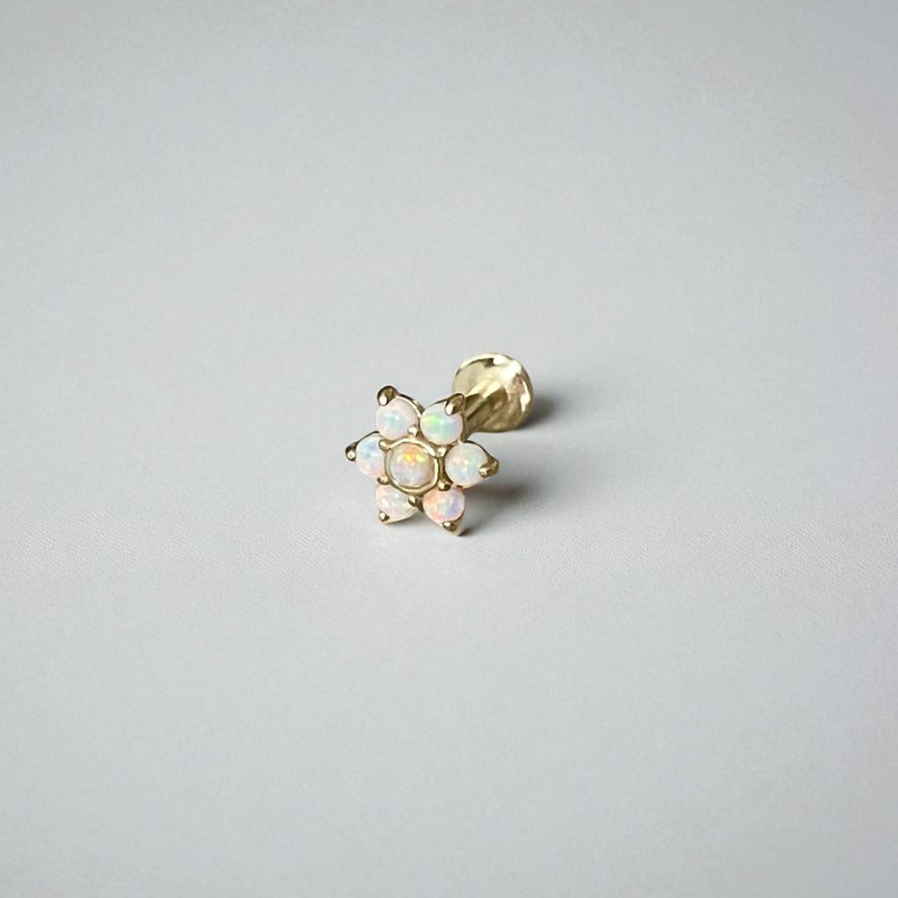 Gold earring with opal stones on a light gray background