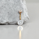 Gold belly button ring with clear gemstone on a gray surface