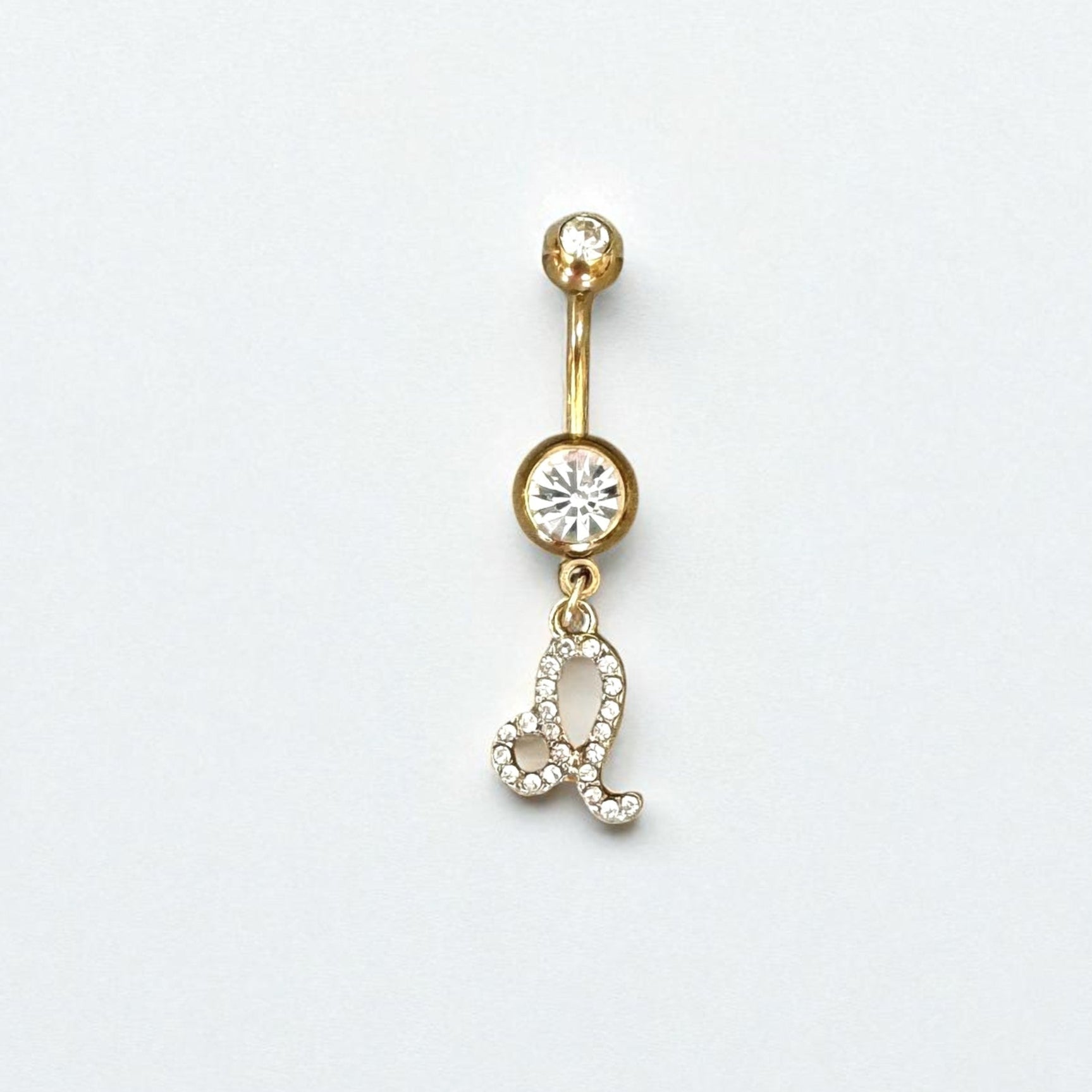 Gold belly button ring with zodiac sign gemstones on a white background