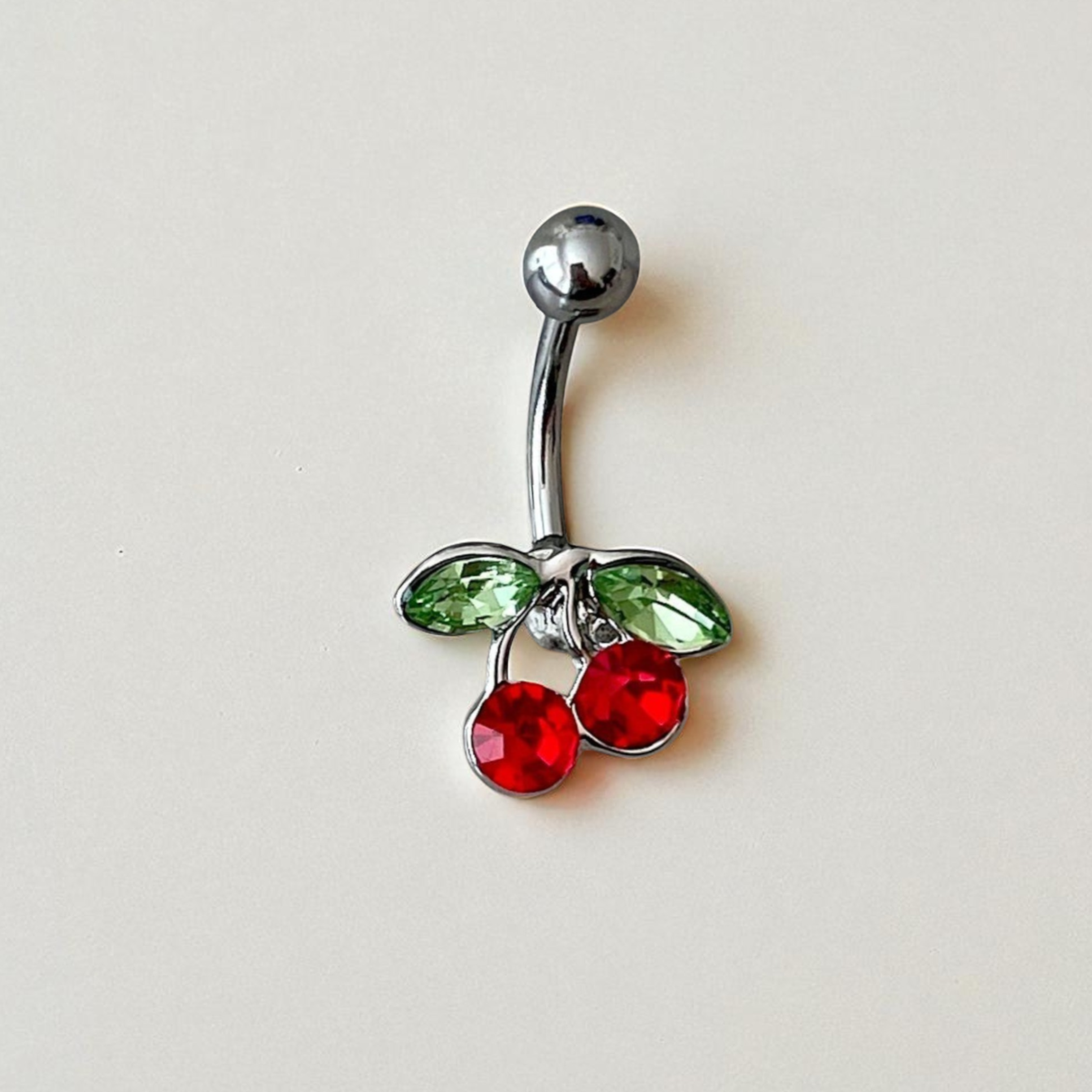 Belly button ring with cherry design on a light gray background