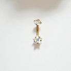 Gold belly button ring with a clear star CZ on a white background