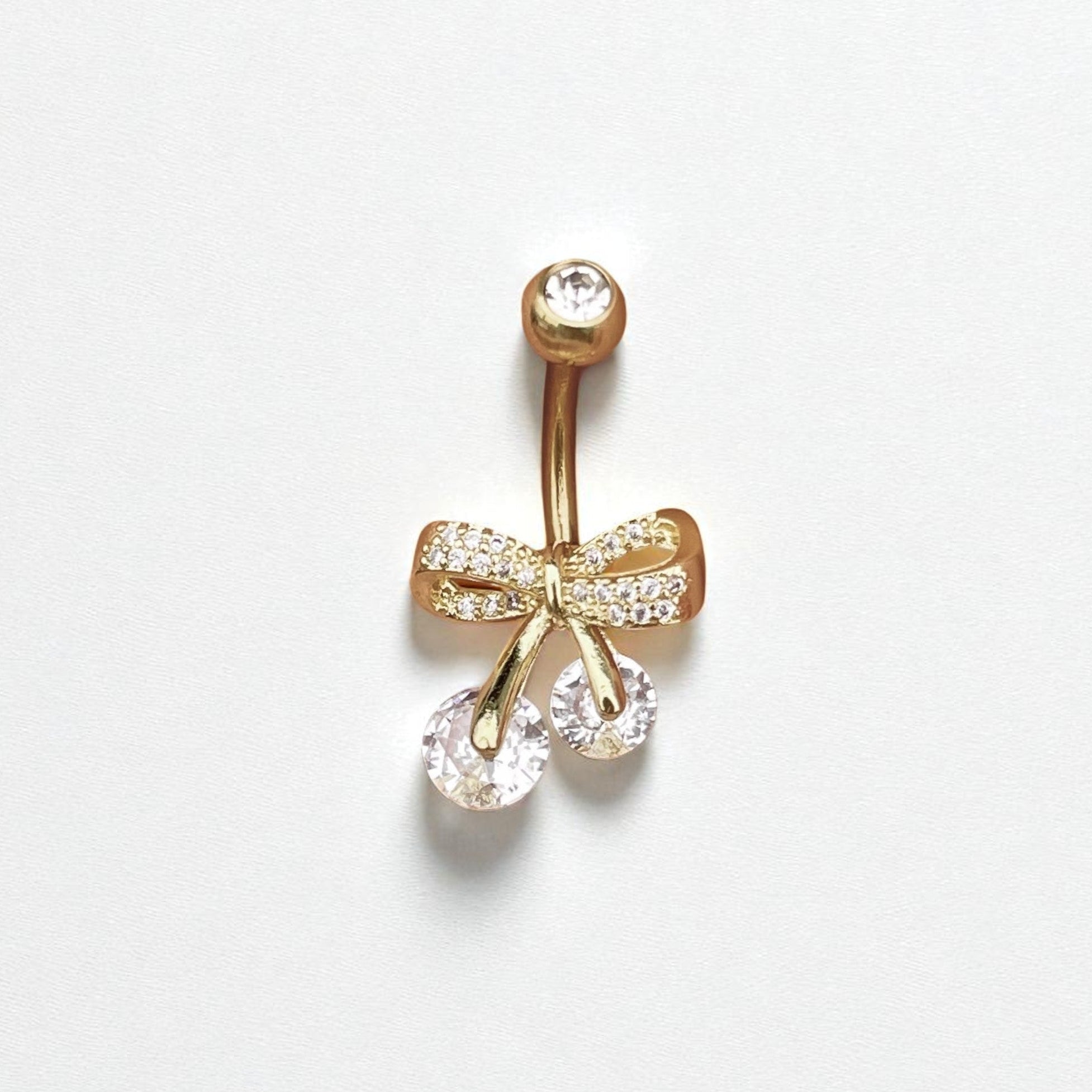 Gold bow-shaped belly button ring with clear gemstones on a white background