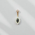 Gold belly button ring with black gemstone and white stones on a light gray background