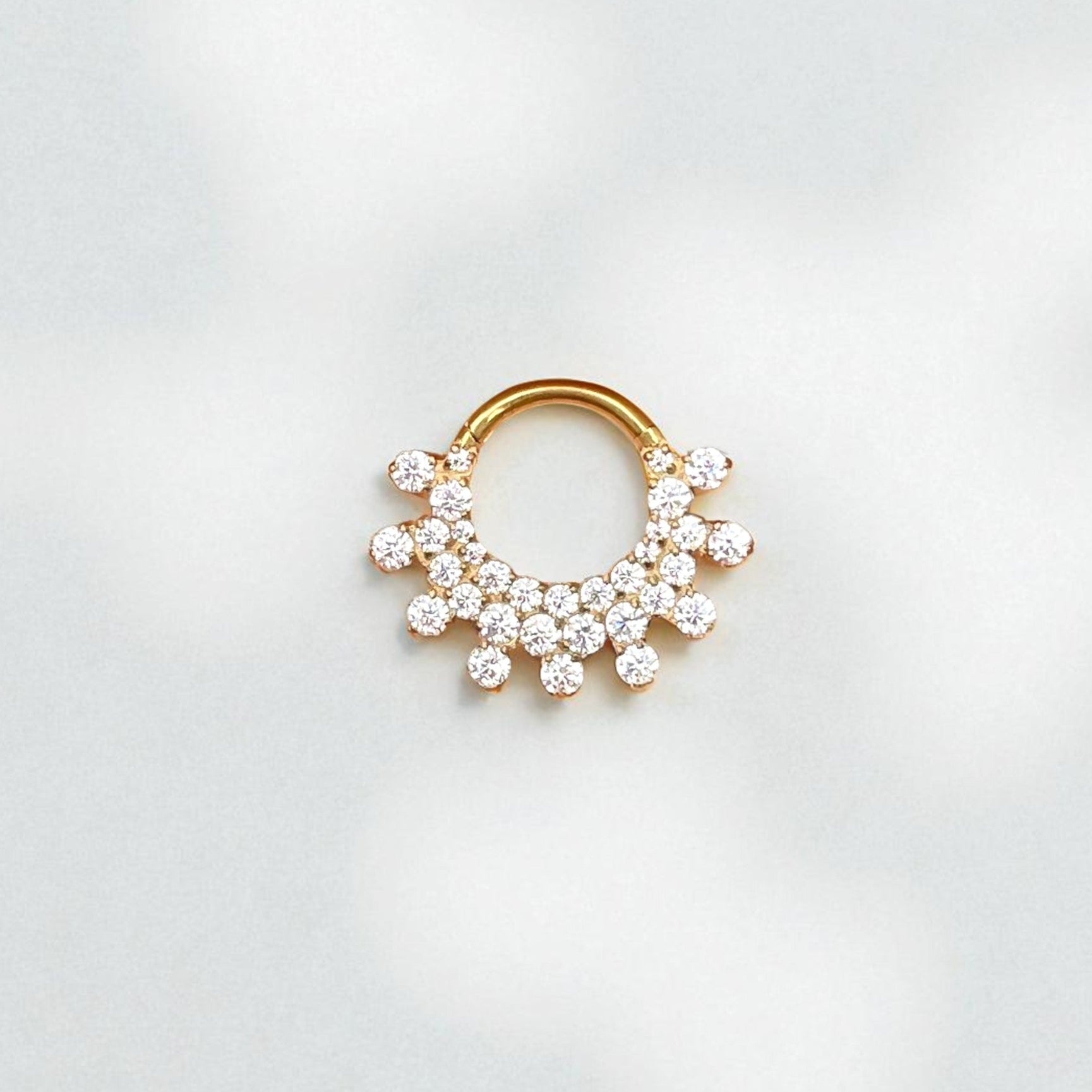 Gold daith earring with embedded crystals on a light gray background