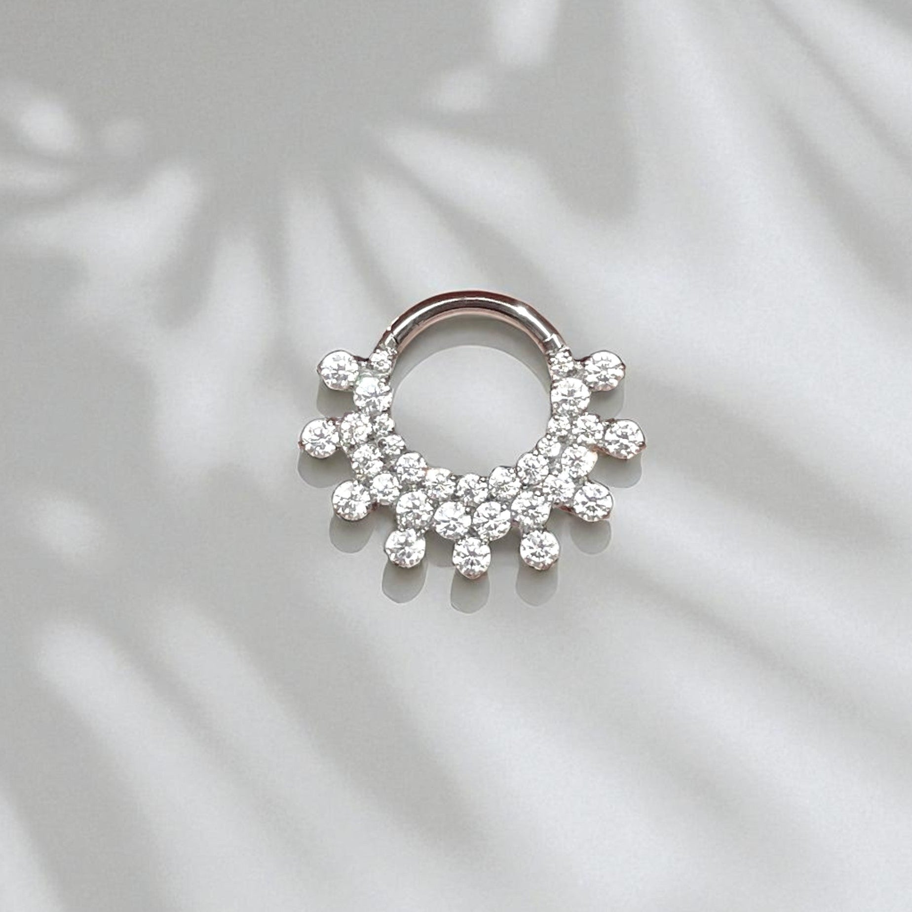 Silver daith earring with clear gemstones on a light background