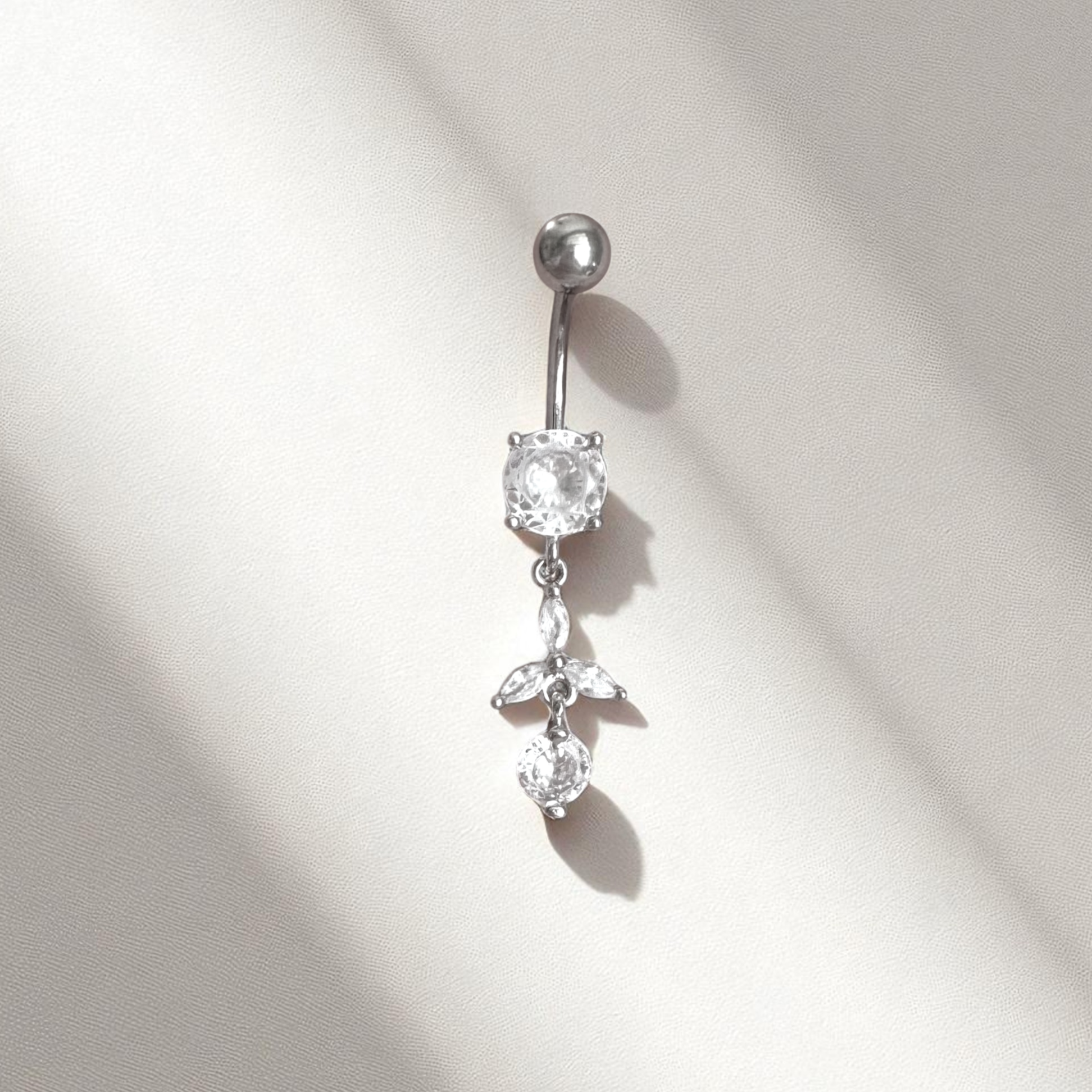 Silver belly button ring with clear gemstones on a light gray background