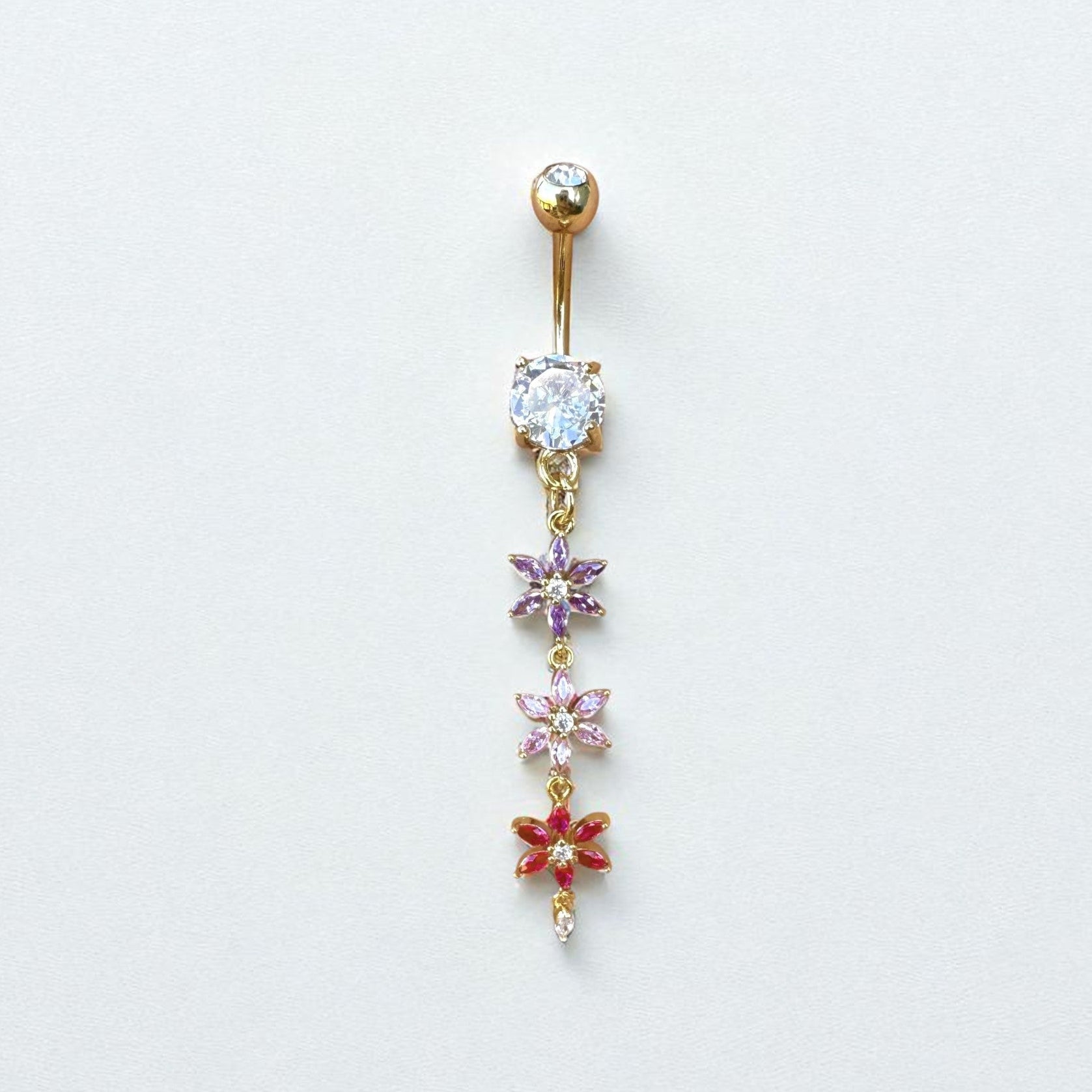Gold belly button ring with floral designs and gemstones on a white background