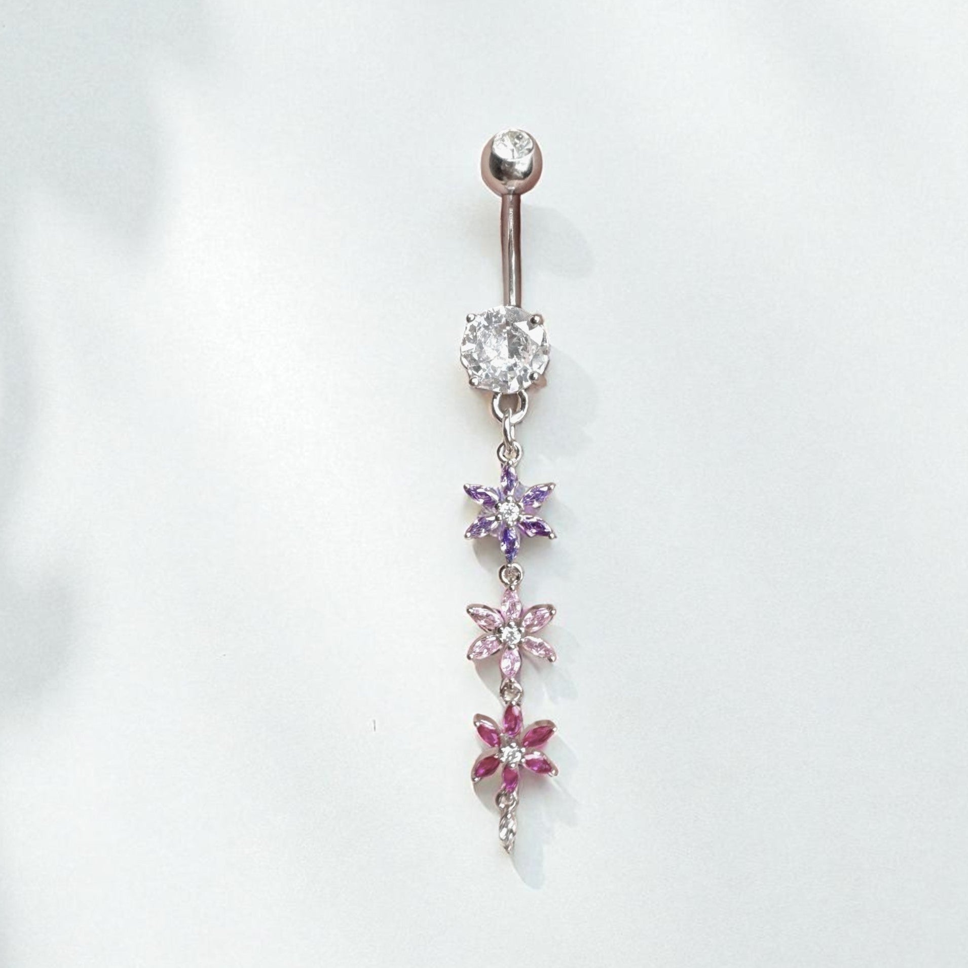 Belly button ring with floral designs and gemstones on a white background