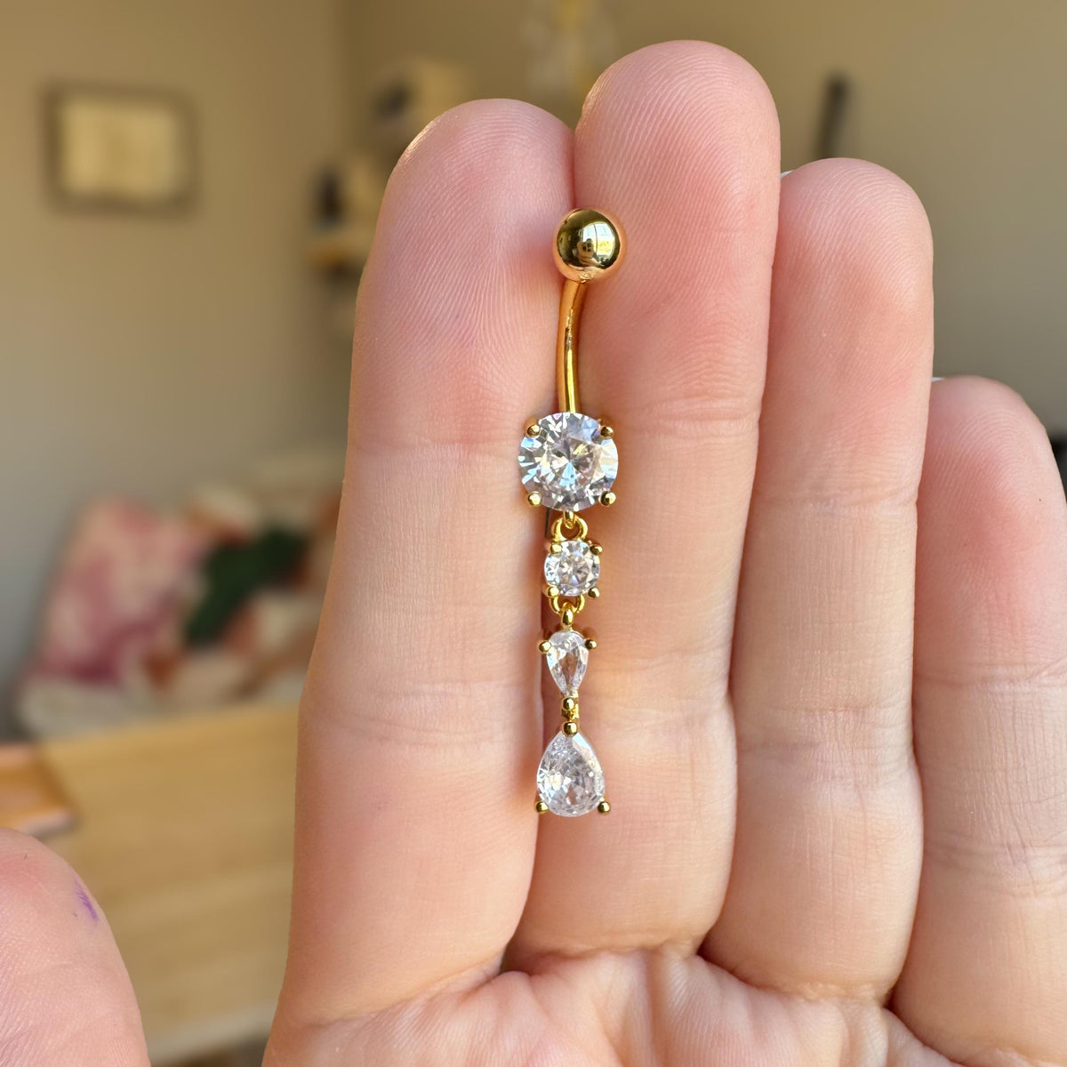 Gold belly button ring with dangling CZ stones in teardrop shapes