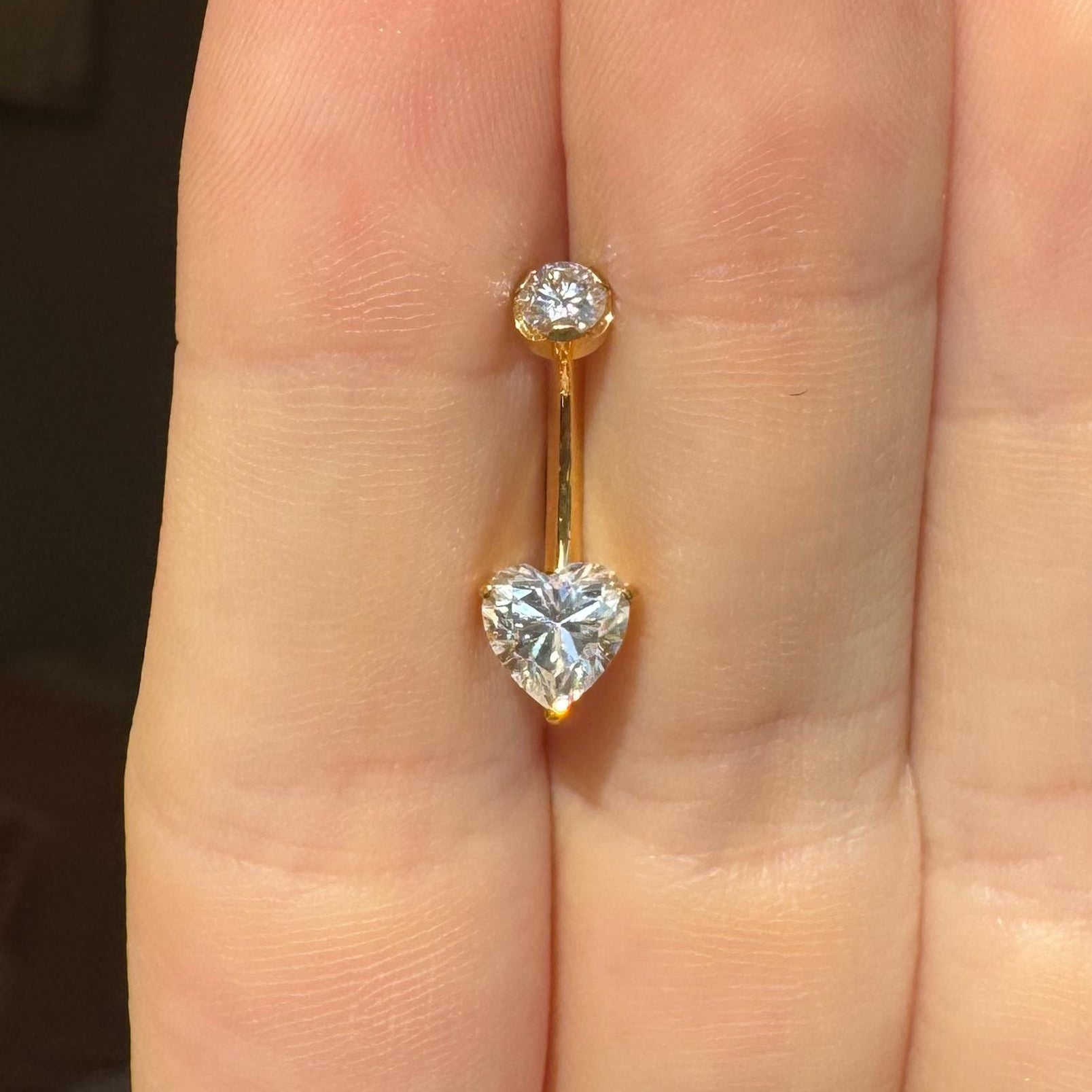 Gold belly button ring with heart-shaped moissanite gemstone on a hand