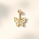 Gold butterfly-shaped belly button ring  on a light beige background