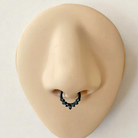 Black septum ring with color shifting dark crystals on a silicone nose