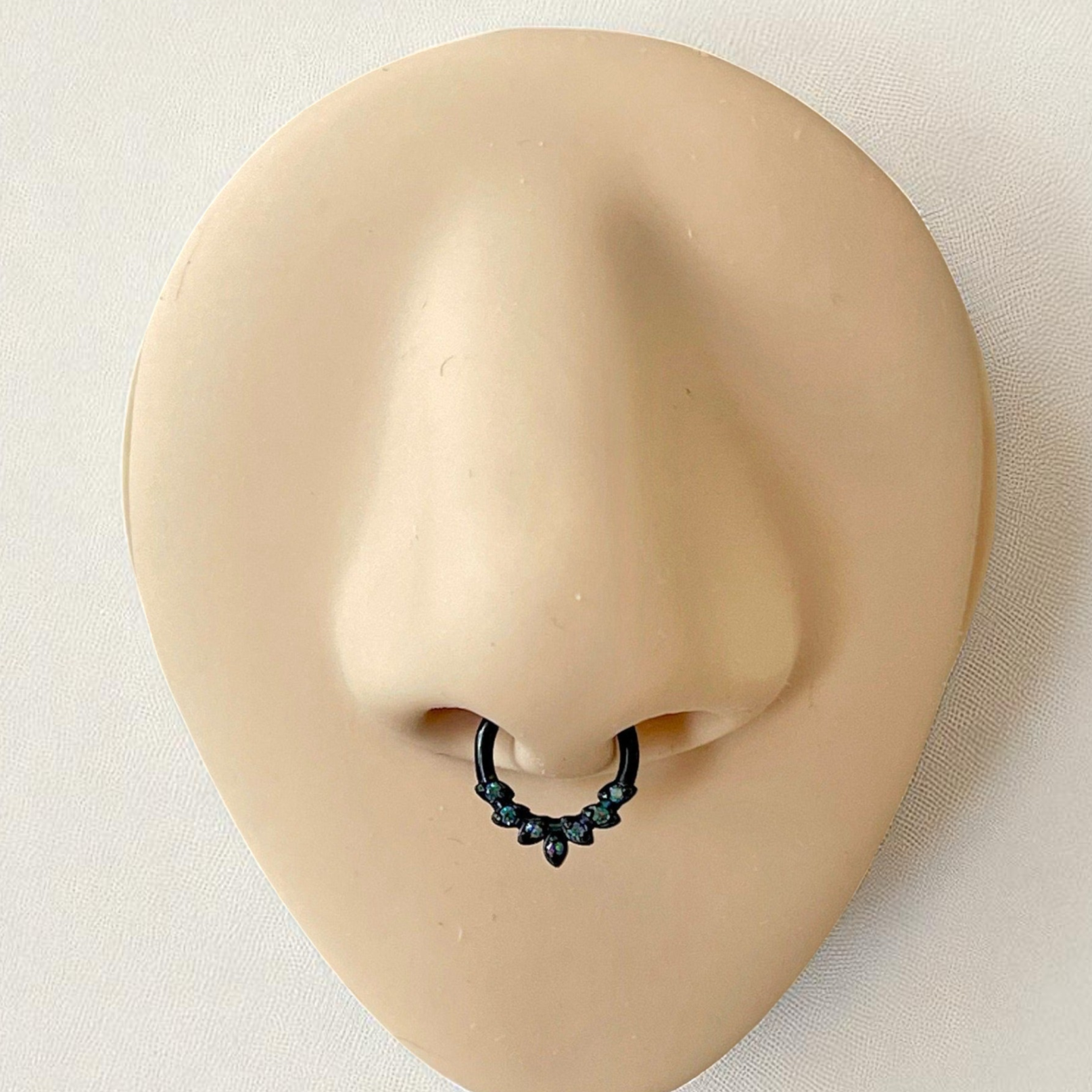 Black septum ring with color shifting dark crystals on a silicone nose