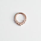 Rose gold sering with small stones on a light gray backgroundtum 