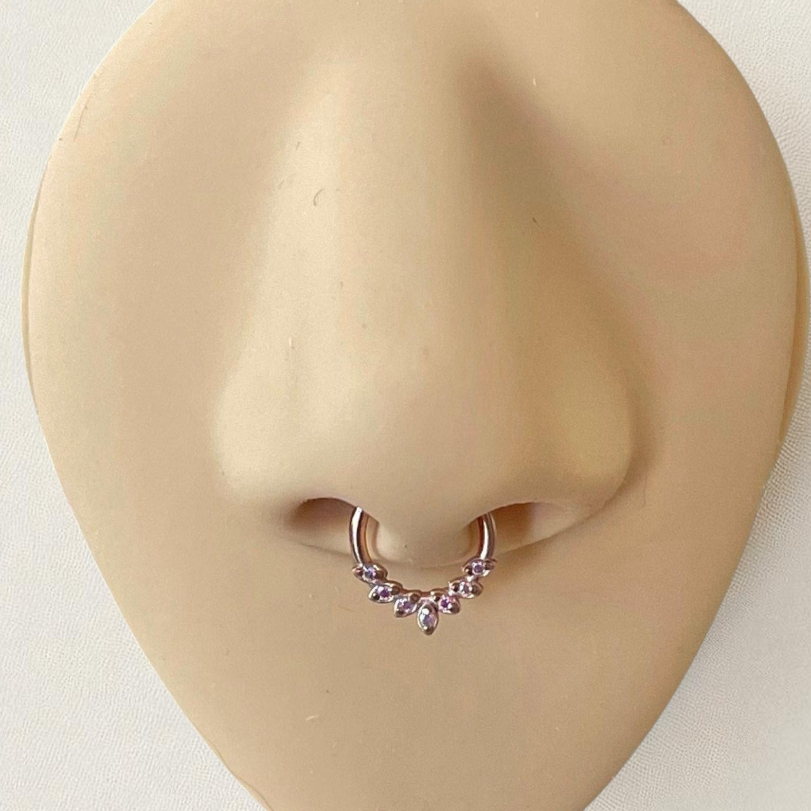 Rose gold septum ring with aurora czs on a silicone nose
