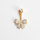 Gold belly button ring with bow design on a white background
