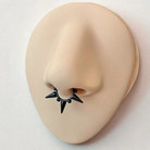 Black spike earring on a mannequin ear with a white background