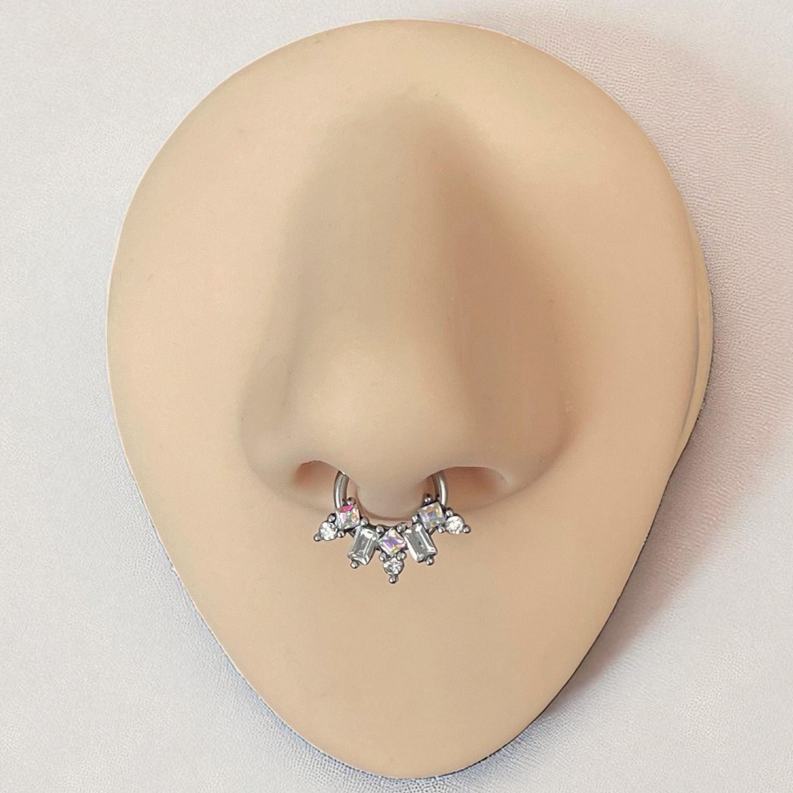 Silver geometric septum ring on a silicone nose
