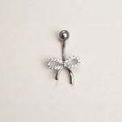 Belly button ring with bow design on a beige background