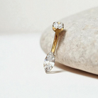 gold belly button ring with clear marquise gem in center
