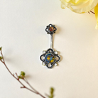 Decorative belly button ring with floral design on a light background
